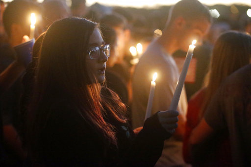 Attendees raise their candles at a candlelight vigil