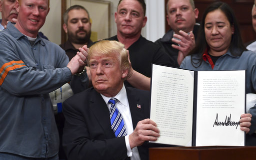 President Donald Trump holds up a proclamation on steel imports