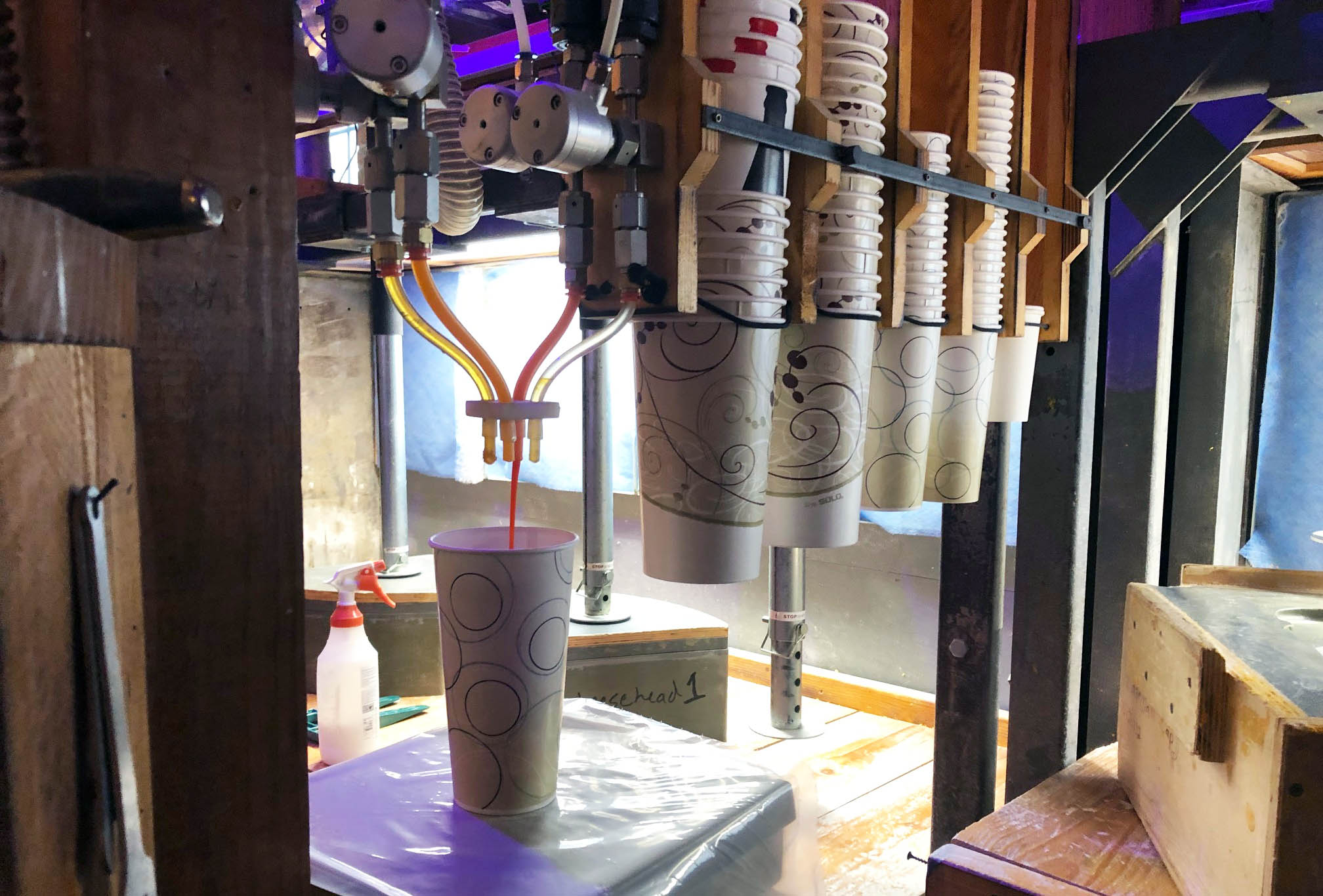 Colored liquid is dispensed into cups for cheesehead hats