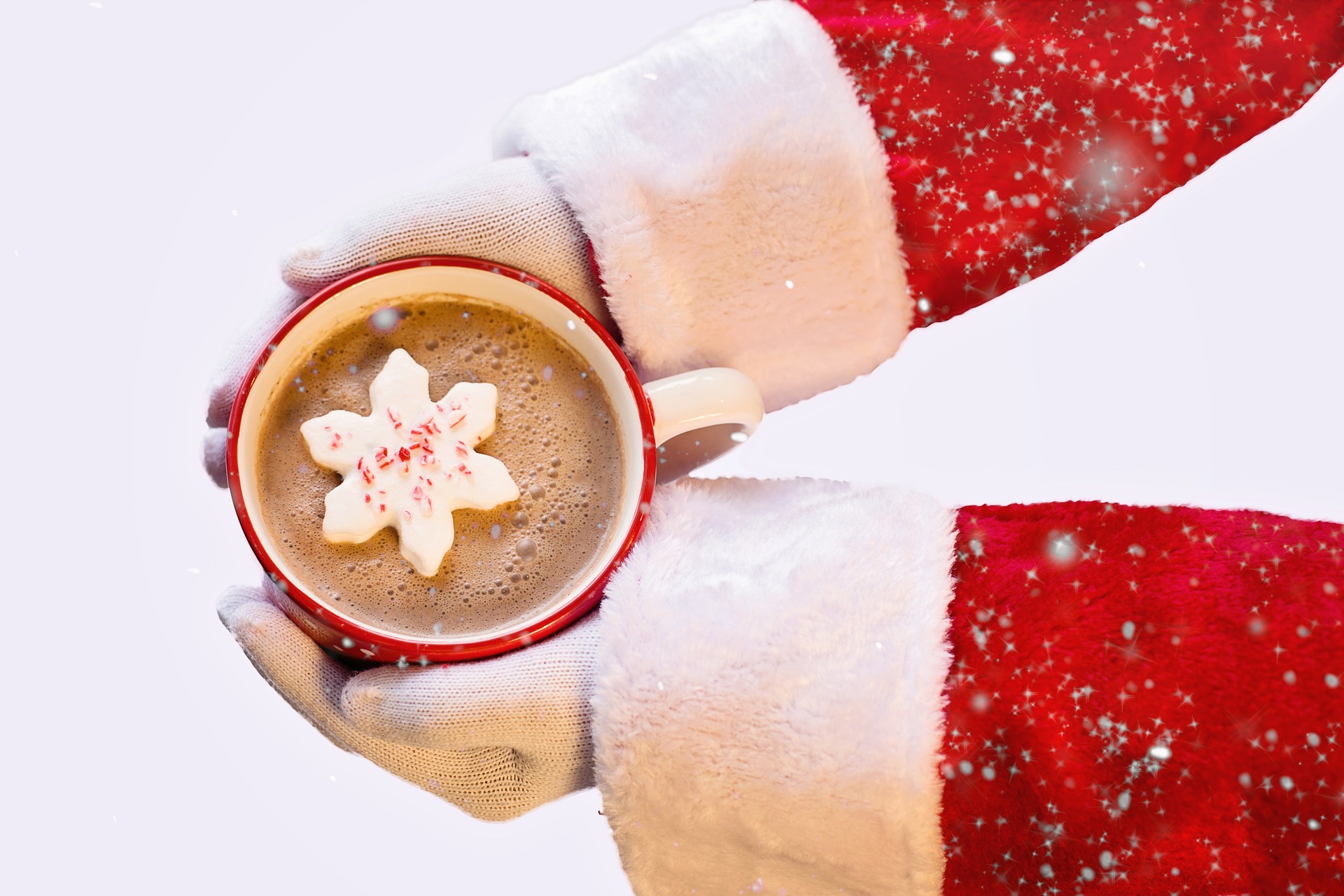 Santa holding a mug of hot chocolate with a snowflake shaped marshmallow.