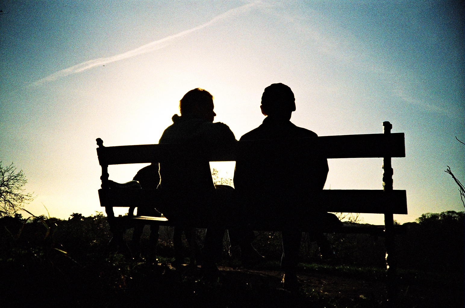 Two people siting on a bench.