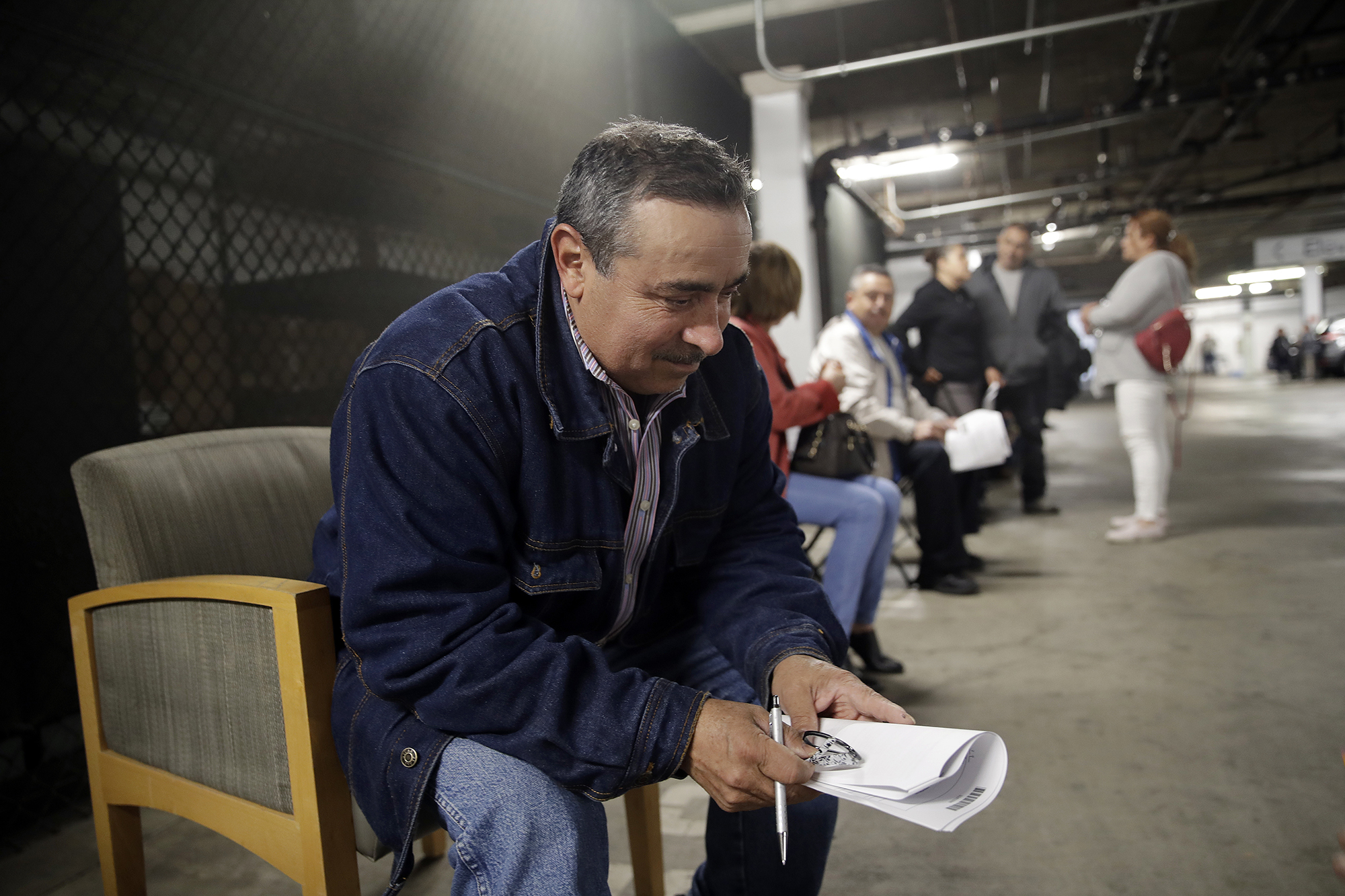 Unionized hospitality workers, including Luis Estrada, wait in line to apply for unemployment