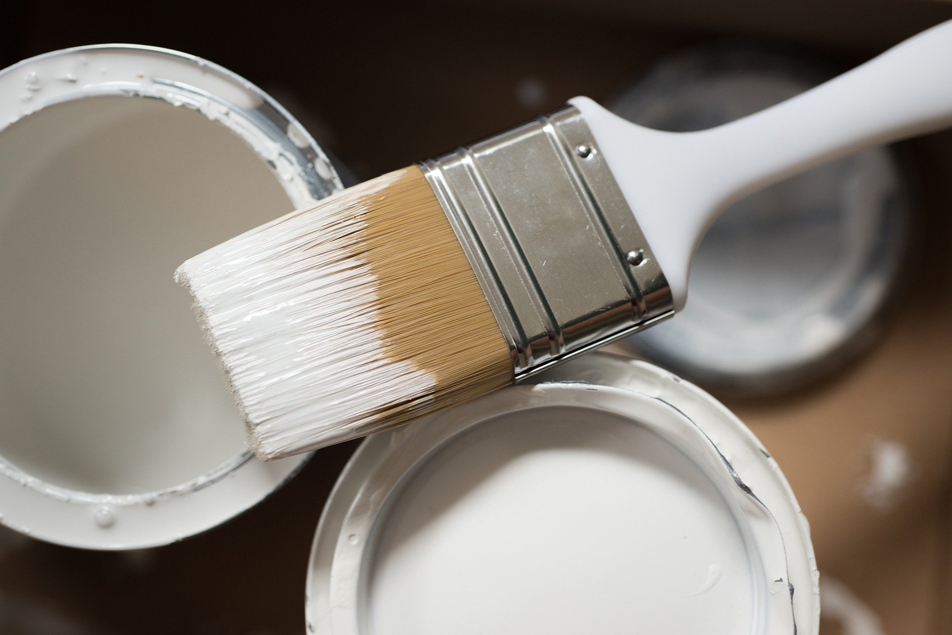 paint brush and cans of white paint