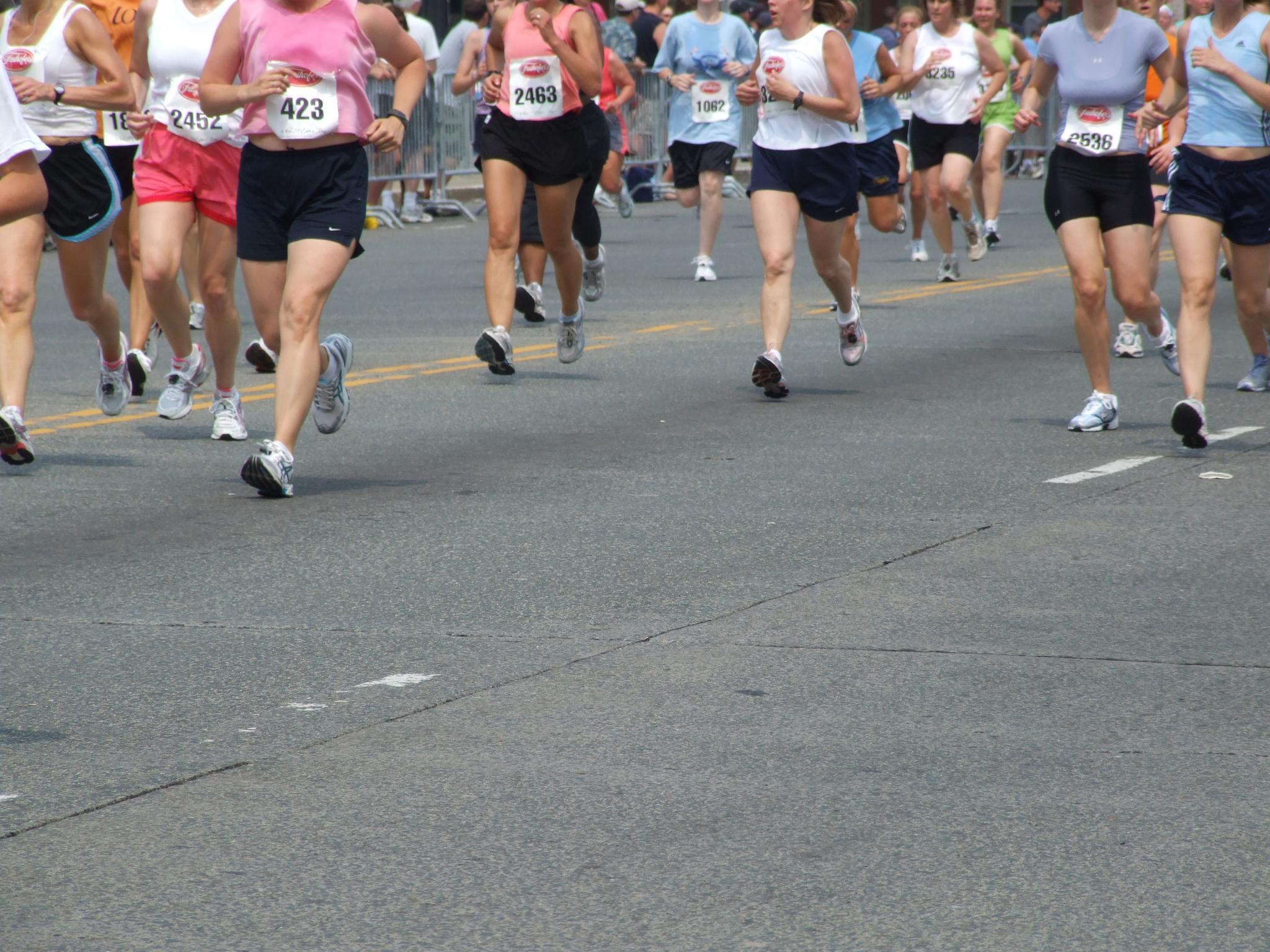 A group of runners in a road race visible from mid waist down.