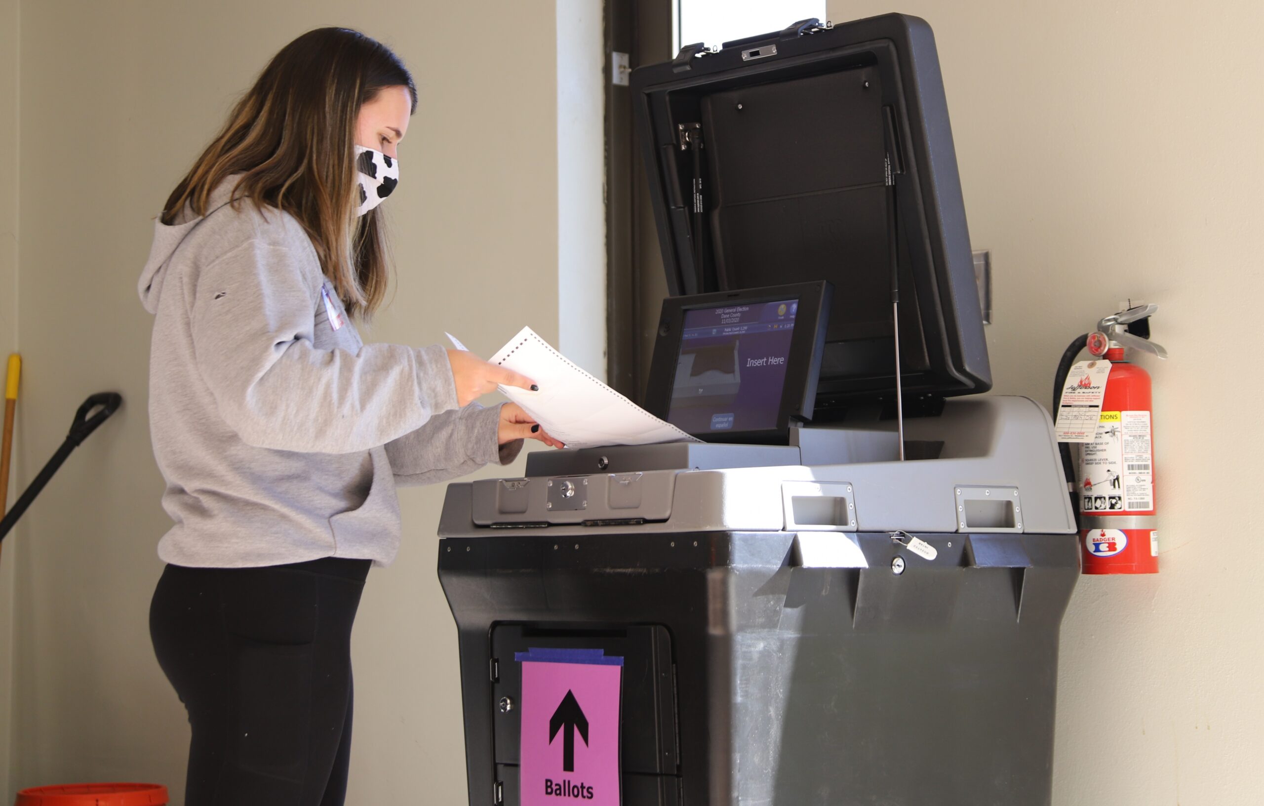 A poll worker inserts absentee ballots into a voting machine at Lakeview Lutheran Church on Madison's north side