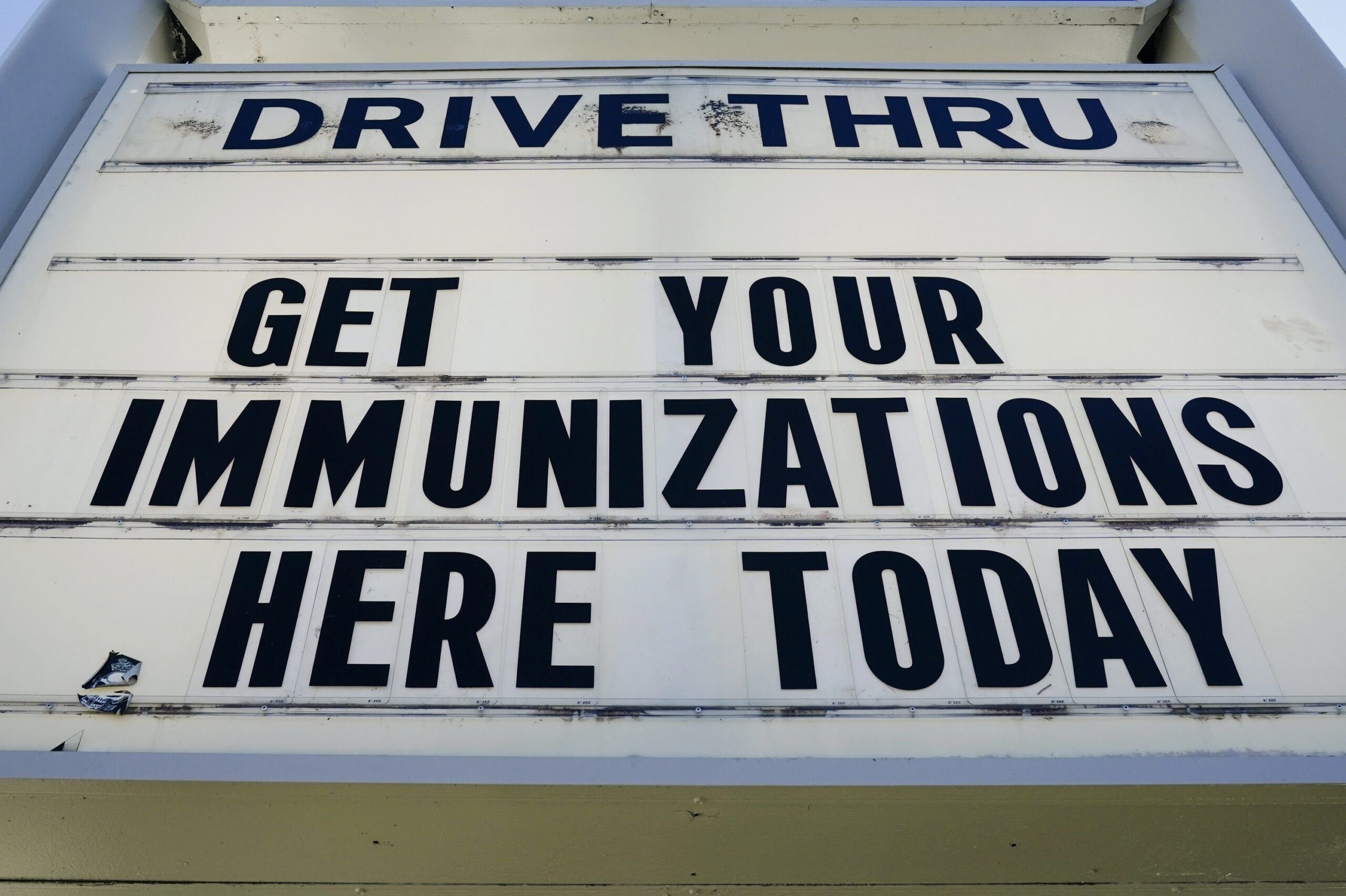 A sign with text about drive-thru vaccinations