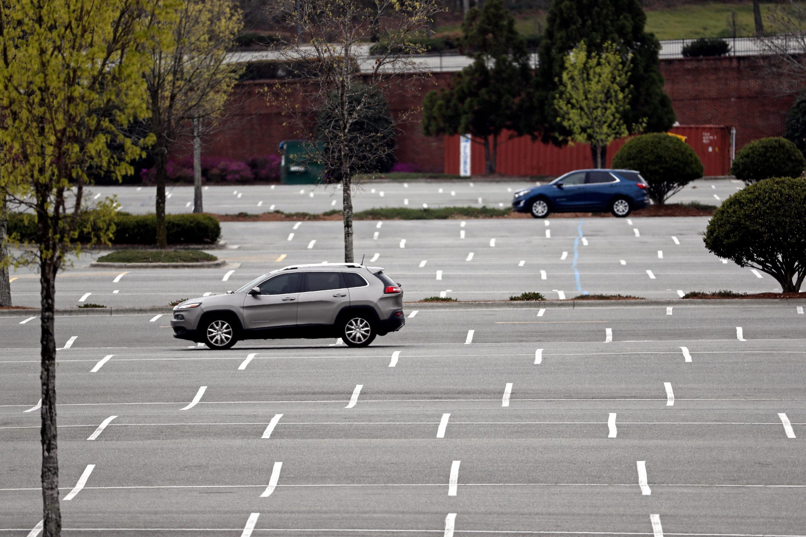 Cars drive through an empty parking lot