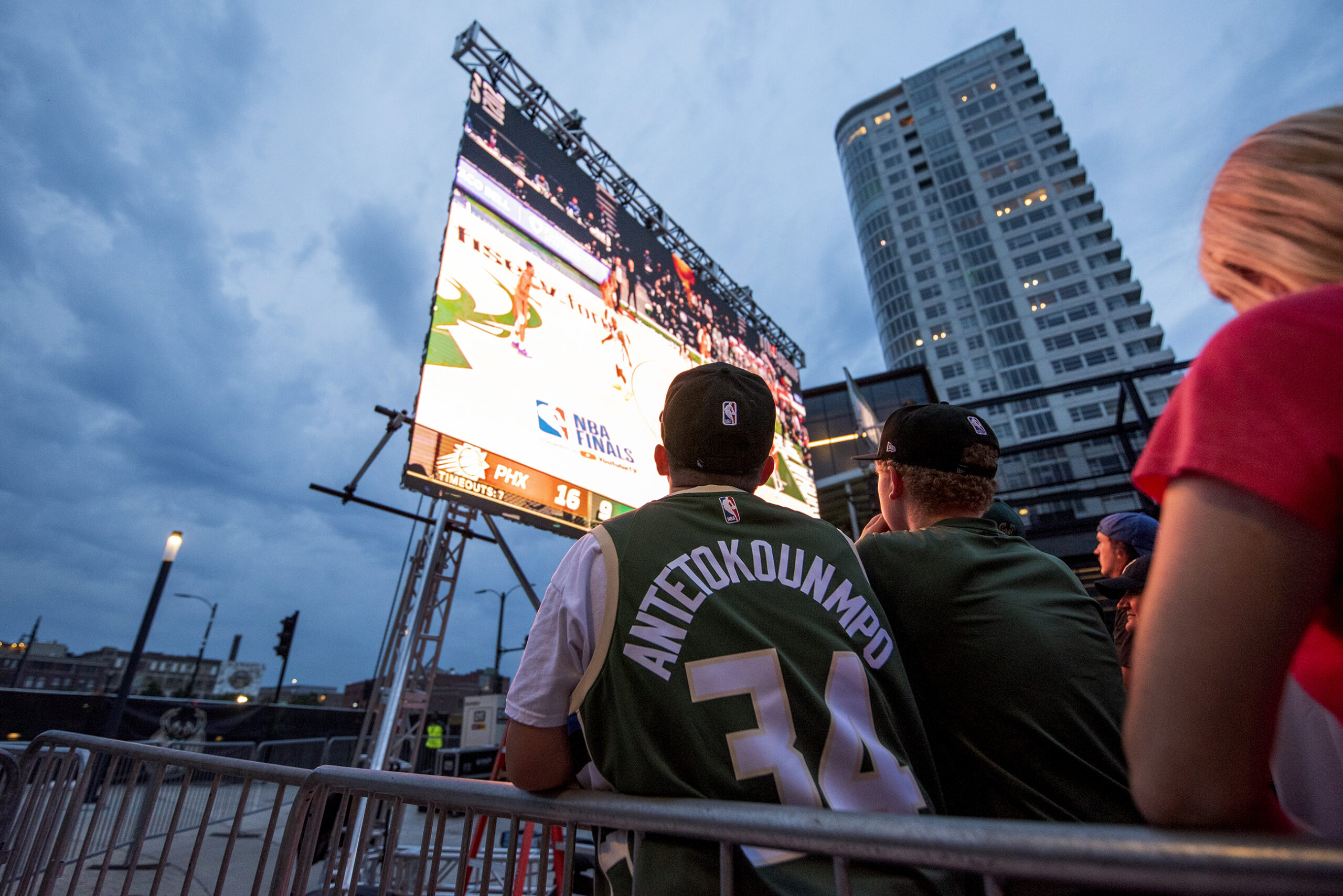 A dark cloudy sky can be seen behind a screen showing the Bucks vs. Suns game.