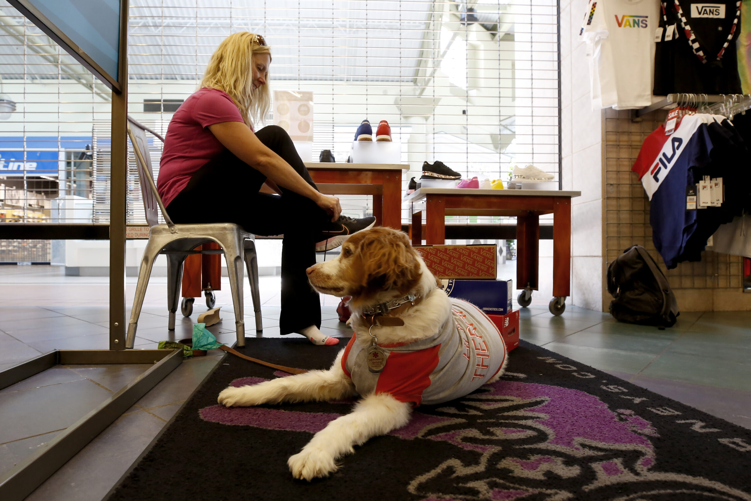 Jamie Riggs is accompanied by her dog, Sadie, as she tries on shoes at Journey's shoe store