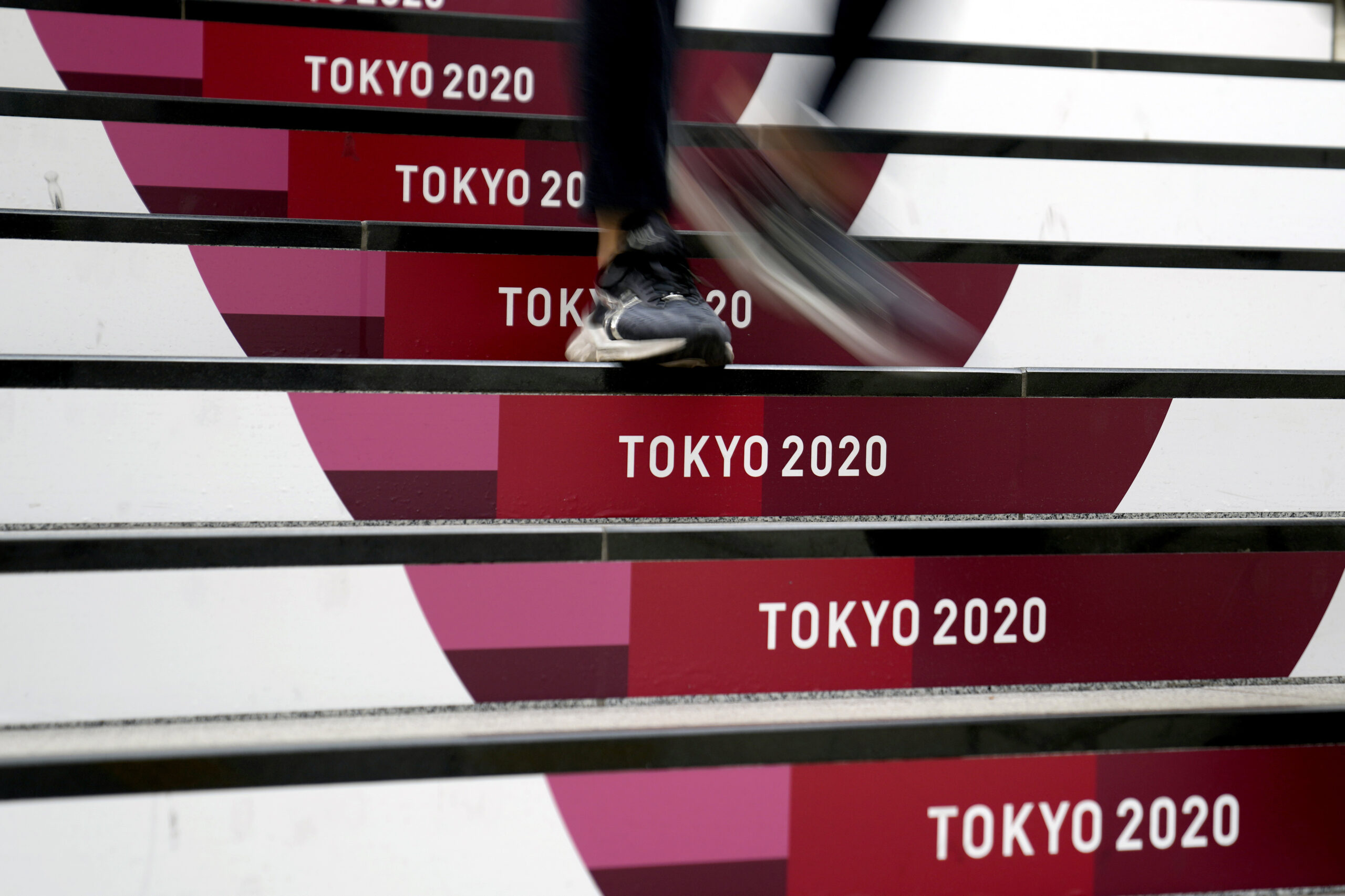A commuter walks down stairs leading to a subway station before the start of the 2020 Summer Olympics, Wednesday