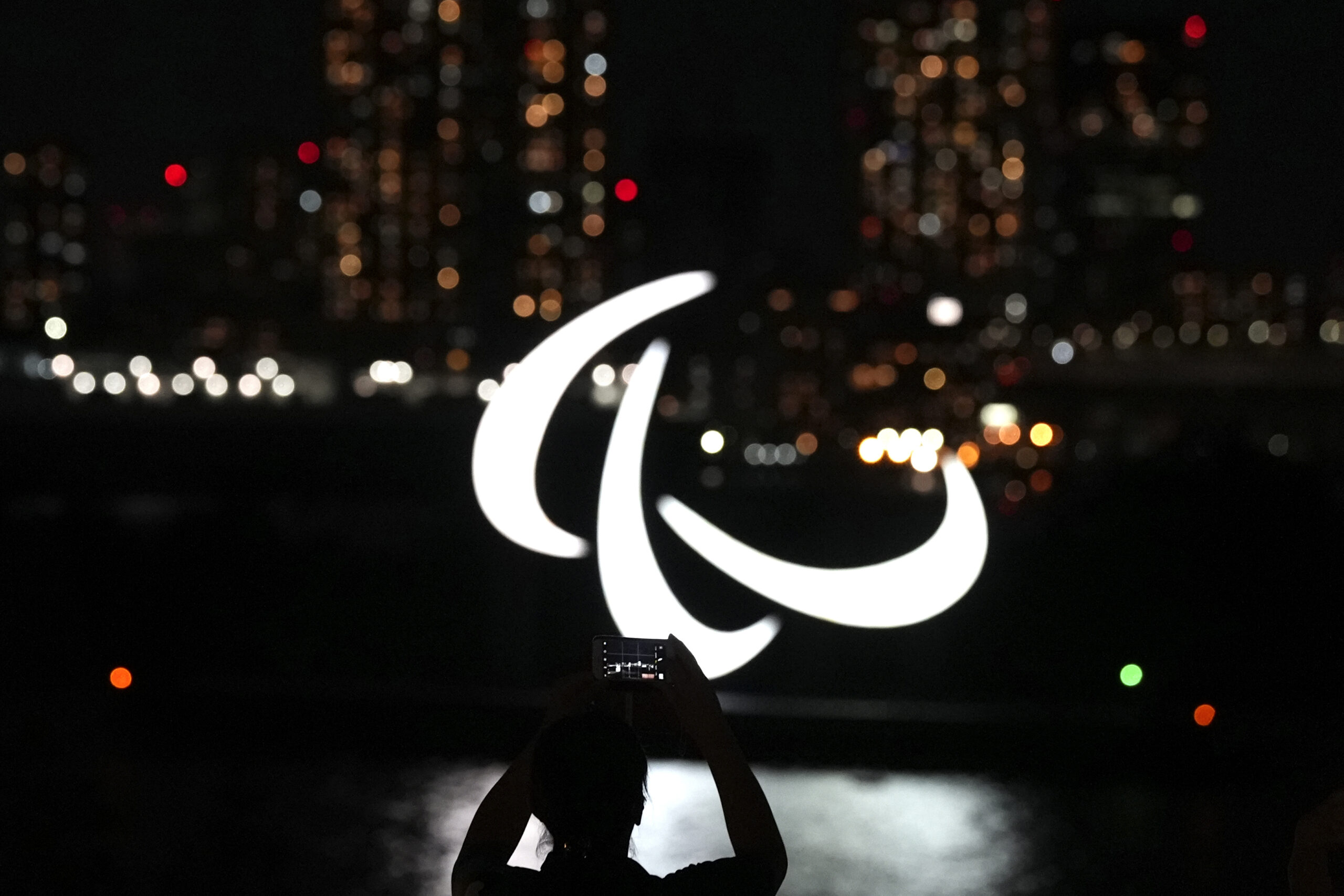 A woman takes a picture of the Paralympics symbol floating in the water in the Odaiba section in Tokyo