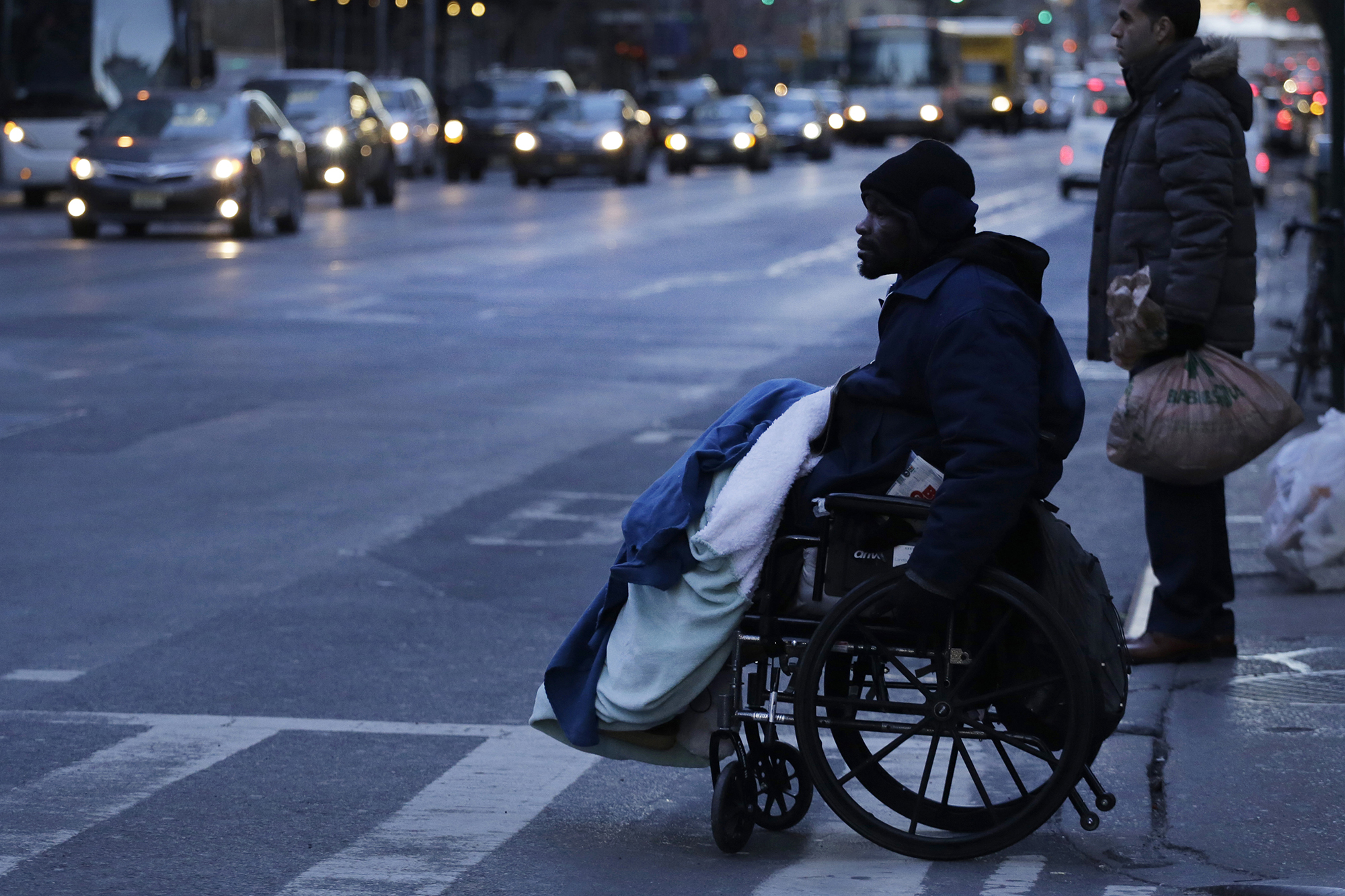 A man in a wheelchair has a blanket across his lap