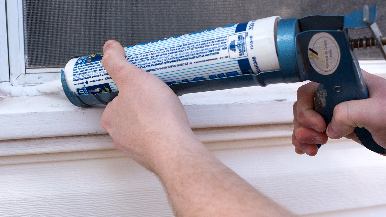 Using caulk to seal window on the outside.