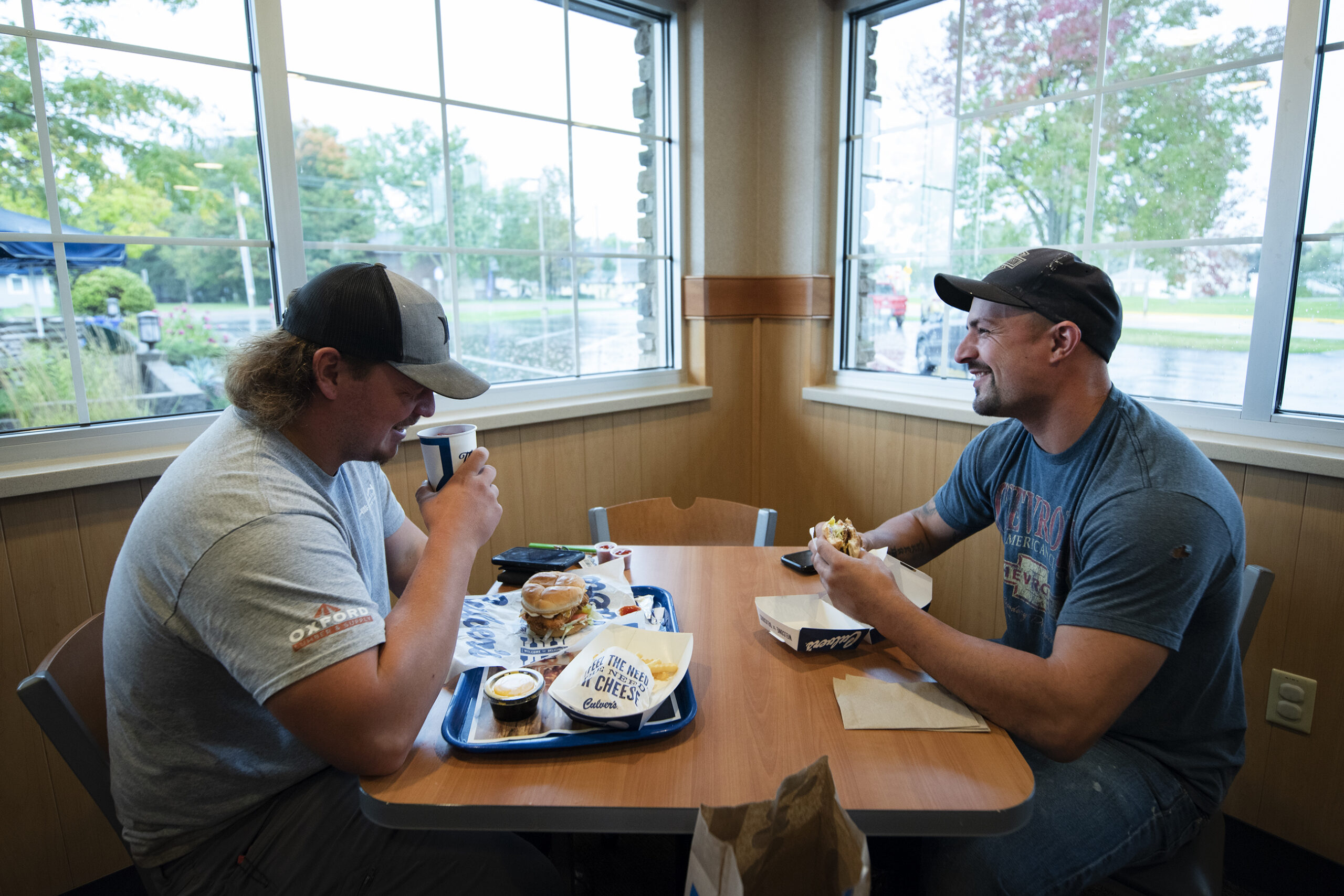 Two customers sit near windows as they eat burgers inside the Culver's dining room.
