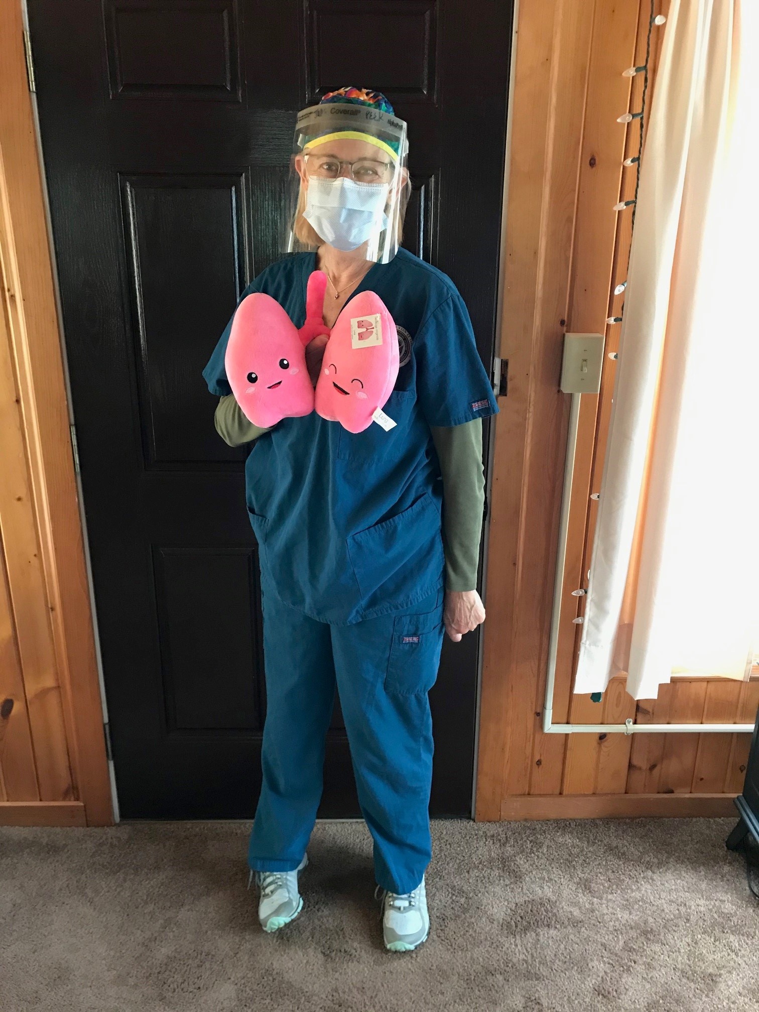 Julia Peek in scrubs and a face mask holds toy lungs