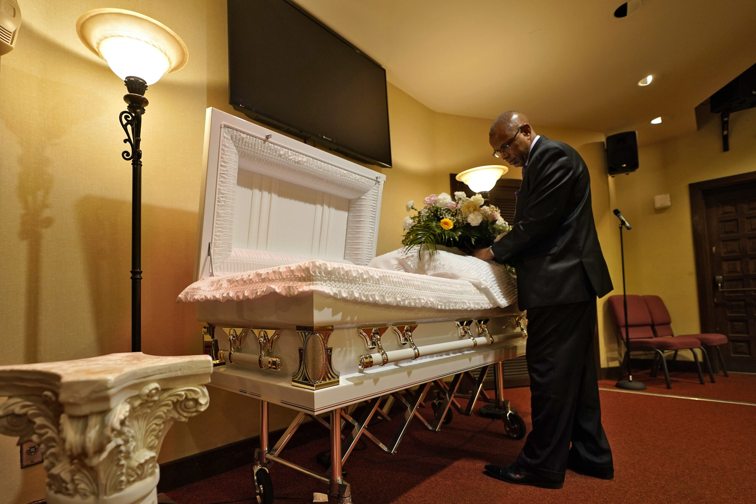 a funeral director arranges flowers on a casket