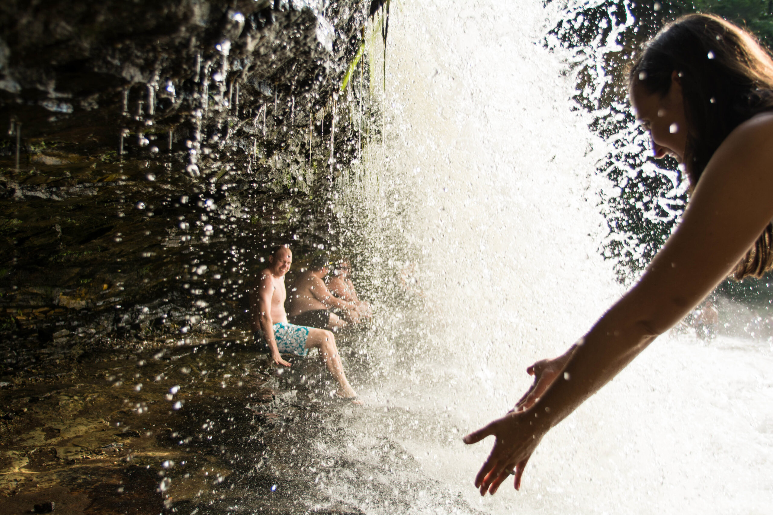 People sit and walk under Willow Falls at Willow River State Park north of Hudson