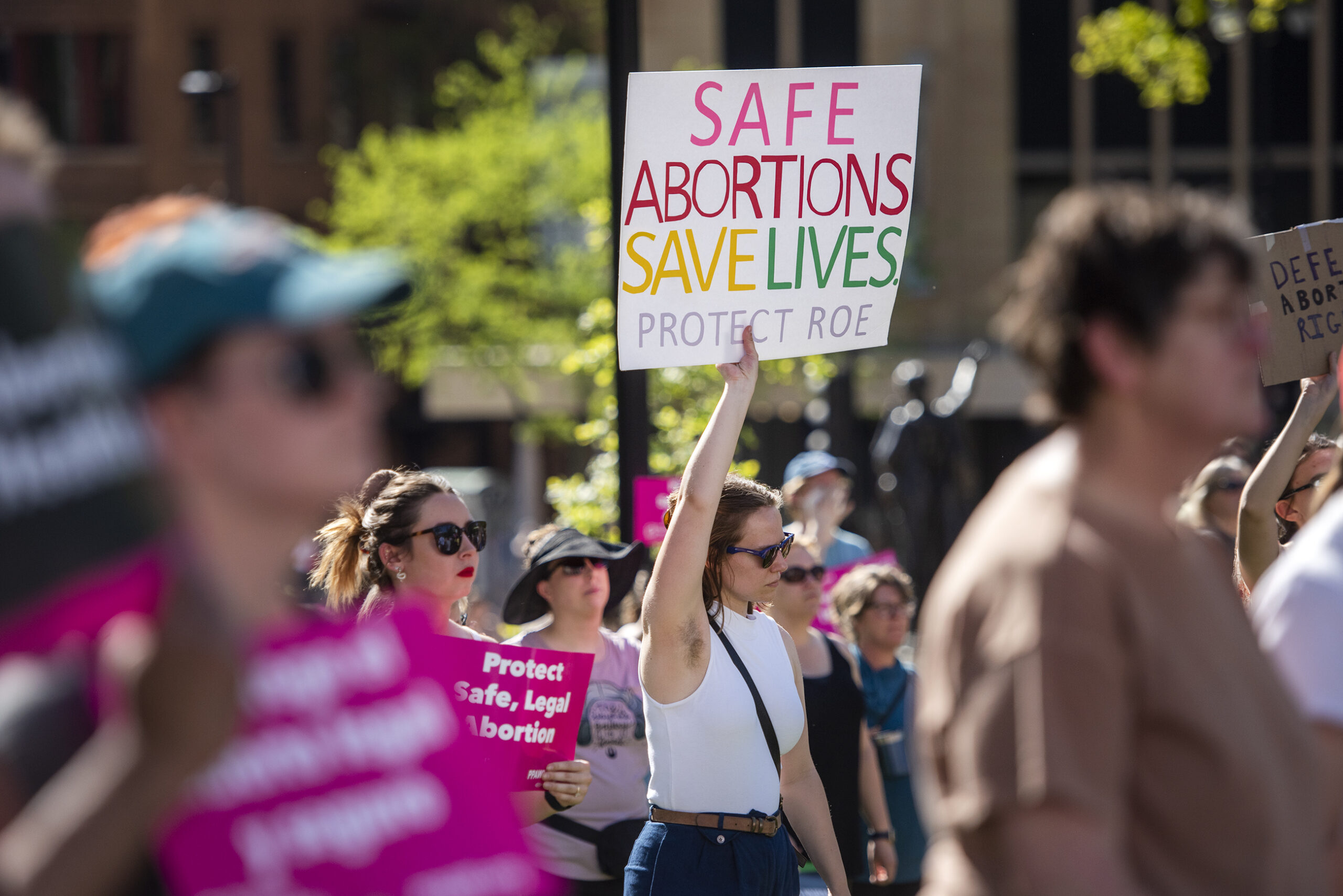 A protester's sign says Safe abortions save lives. Protect Roe.