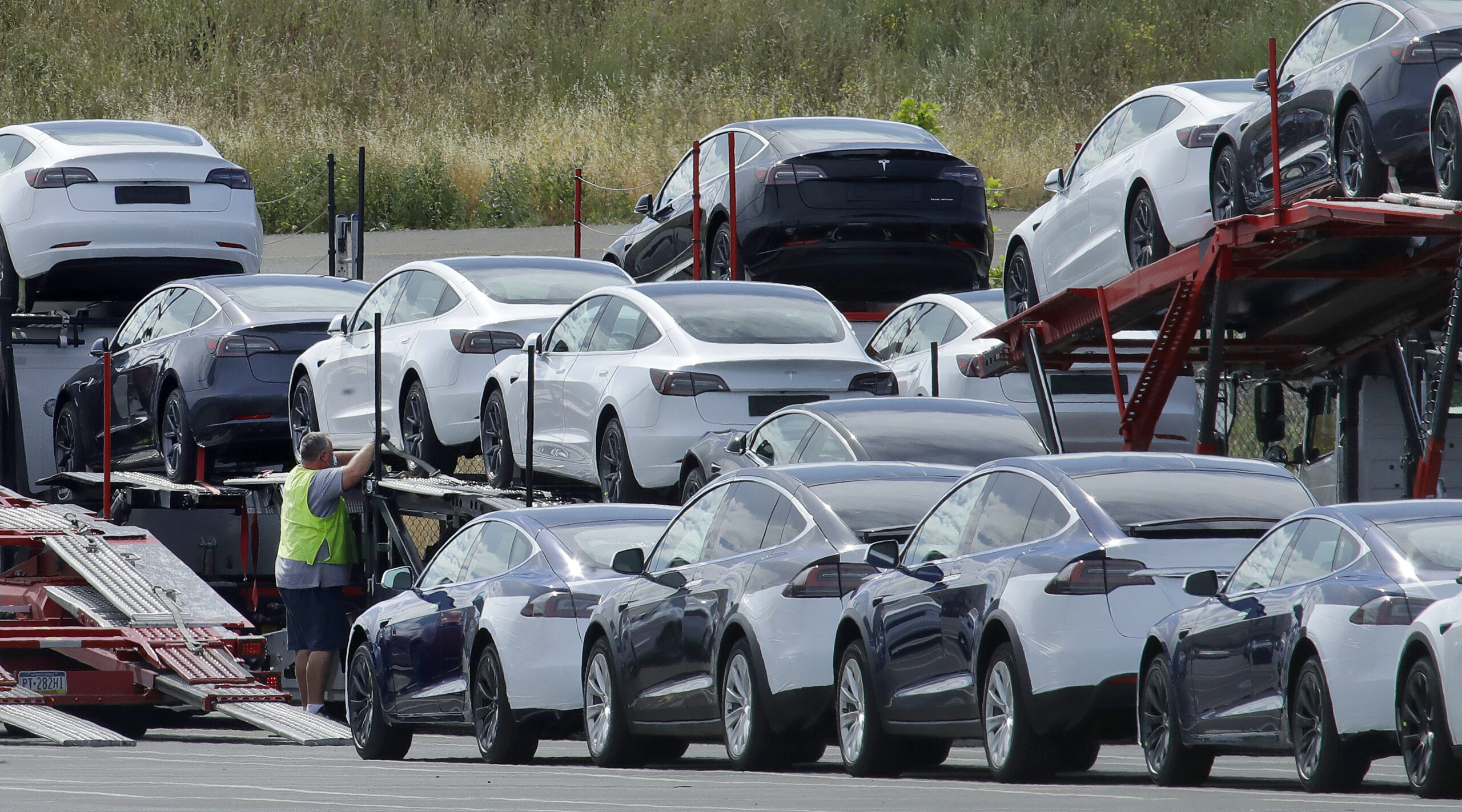 Tesla cars are loaded onto carriers at a Tesla electric car plant