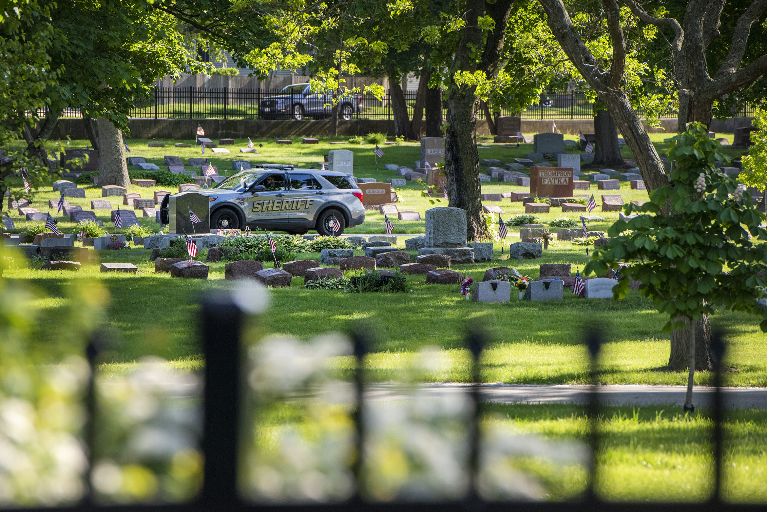 A sheriff deputy drives through a cemetery.