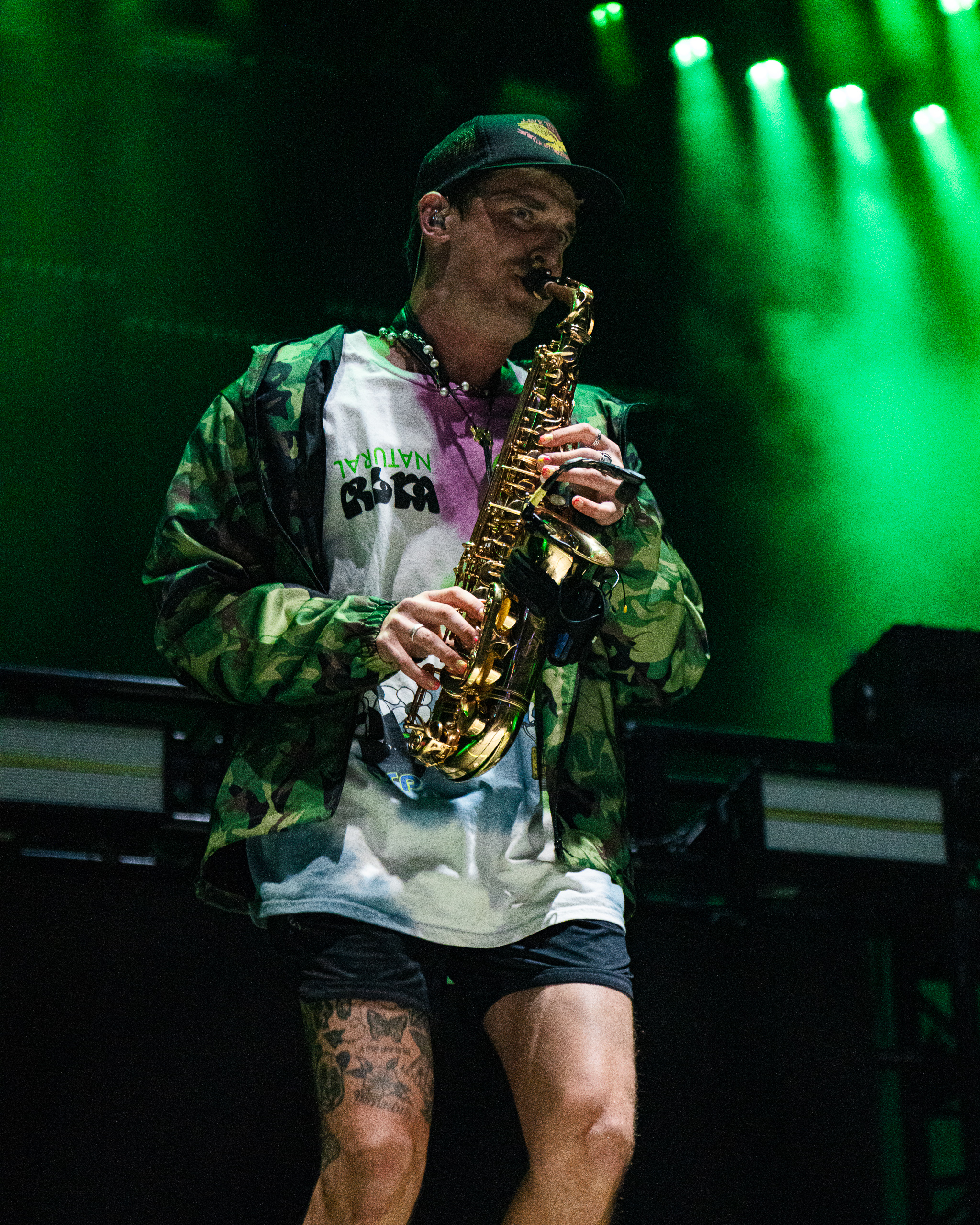 Photo of a man playing saxophone on stage with green lights in the background