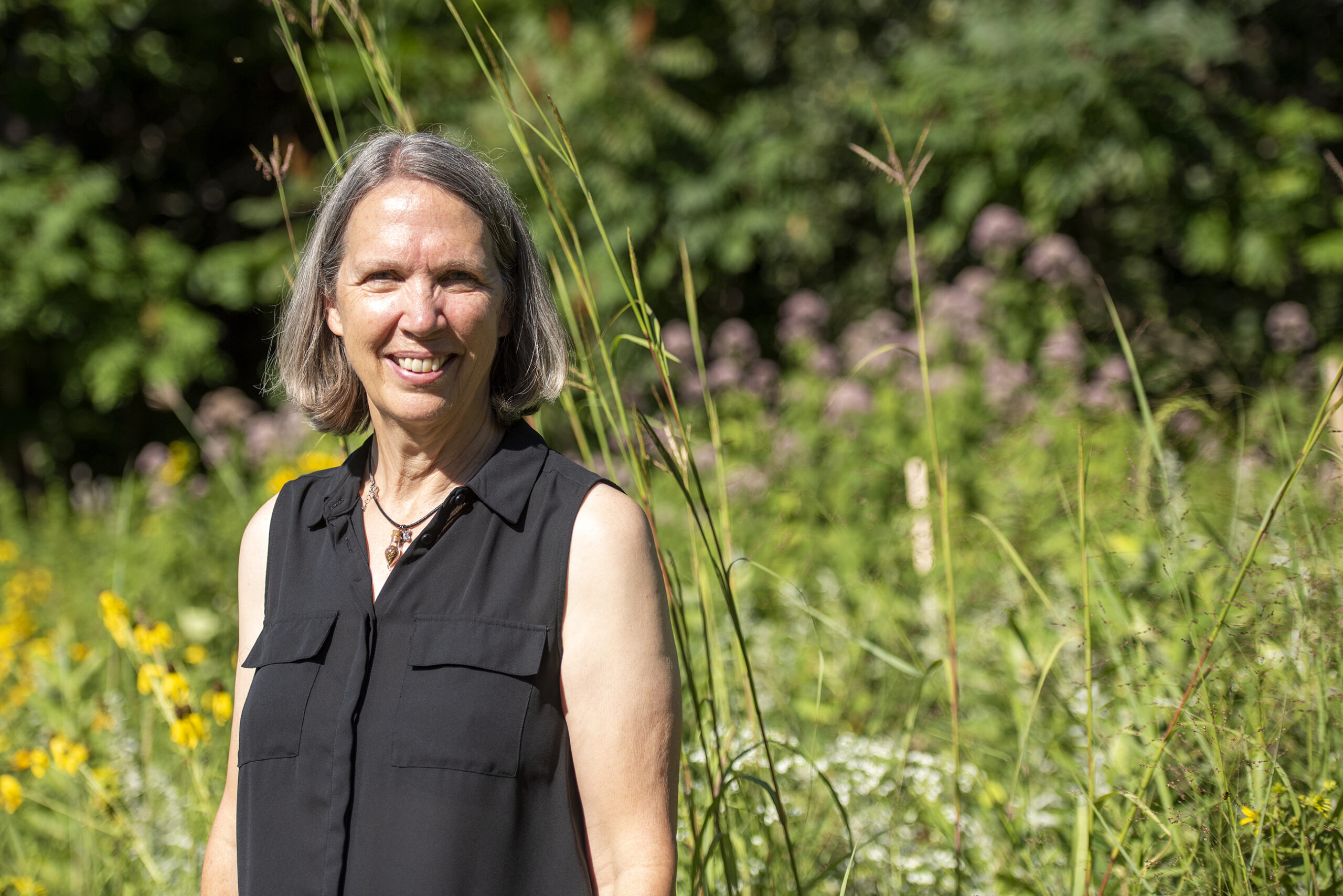 Karen Oberhauser stands in front of greenery at the arboretum.