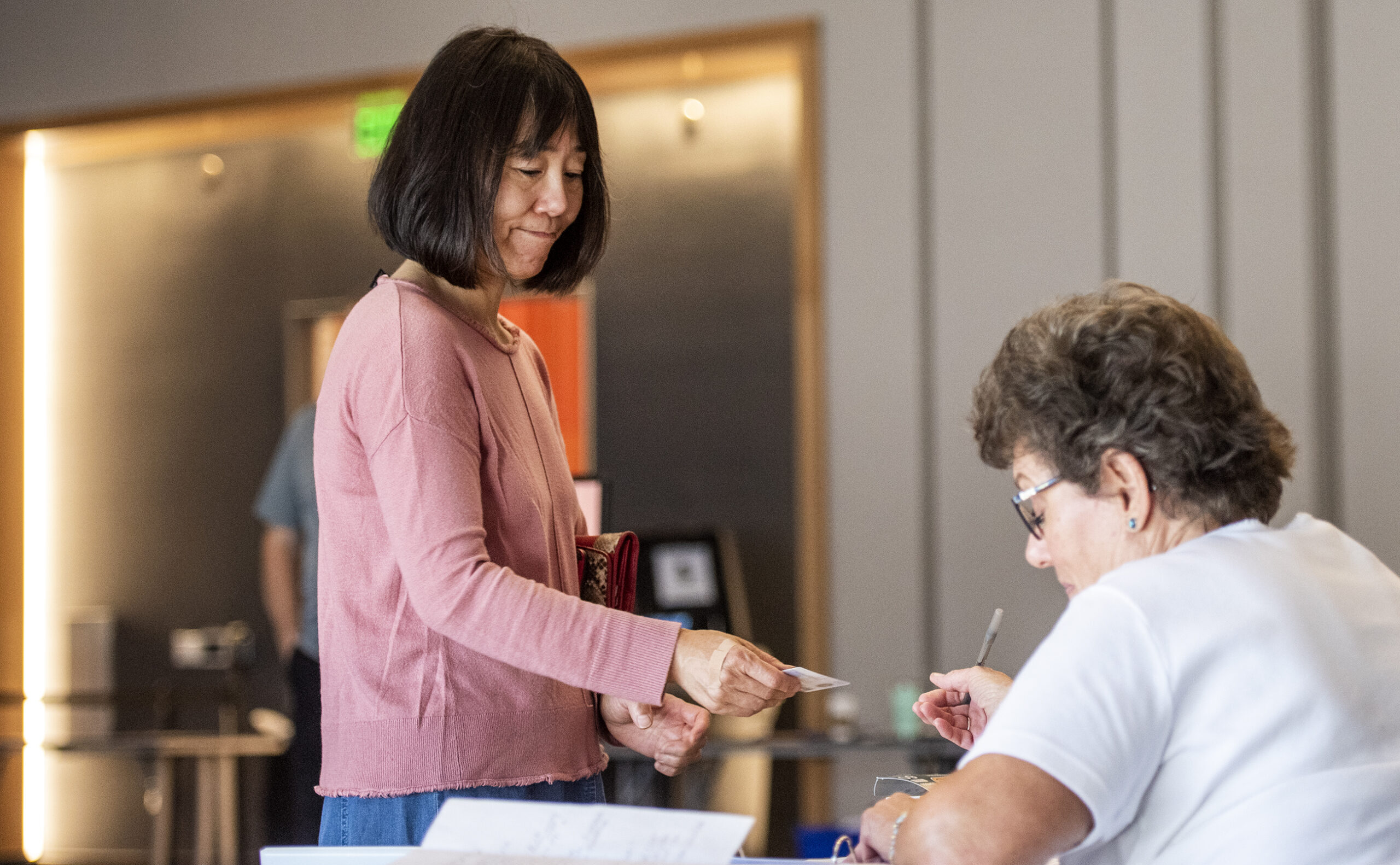 A woman stands at a table as she prepares to vote.