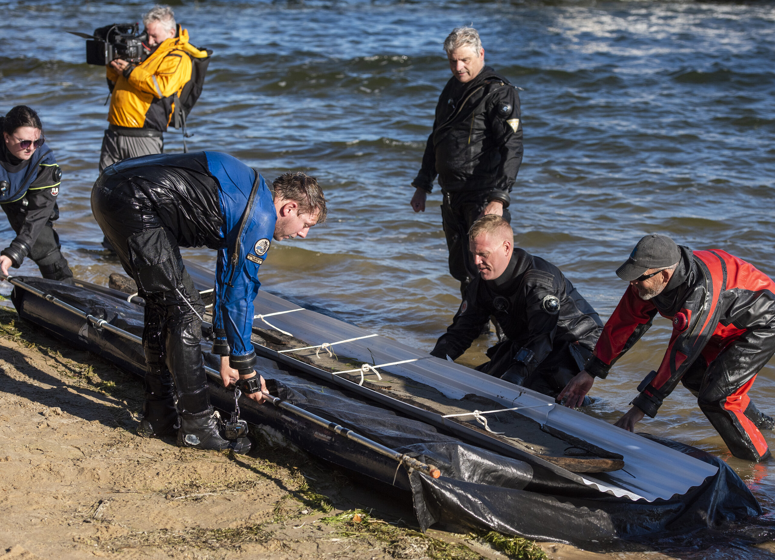 Crew members carefully place the canoe on the shore.