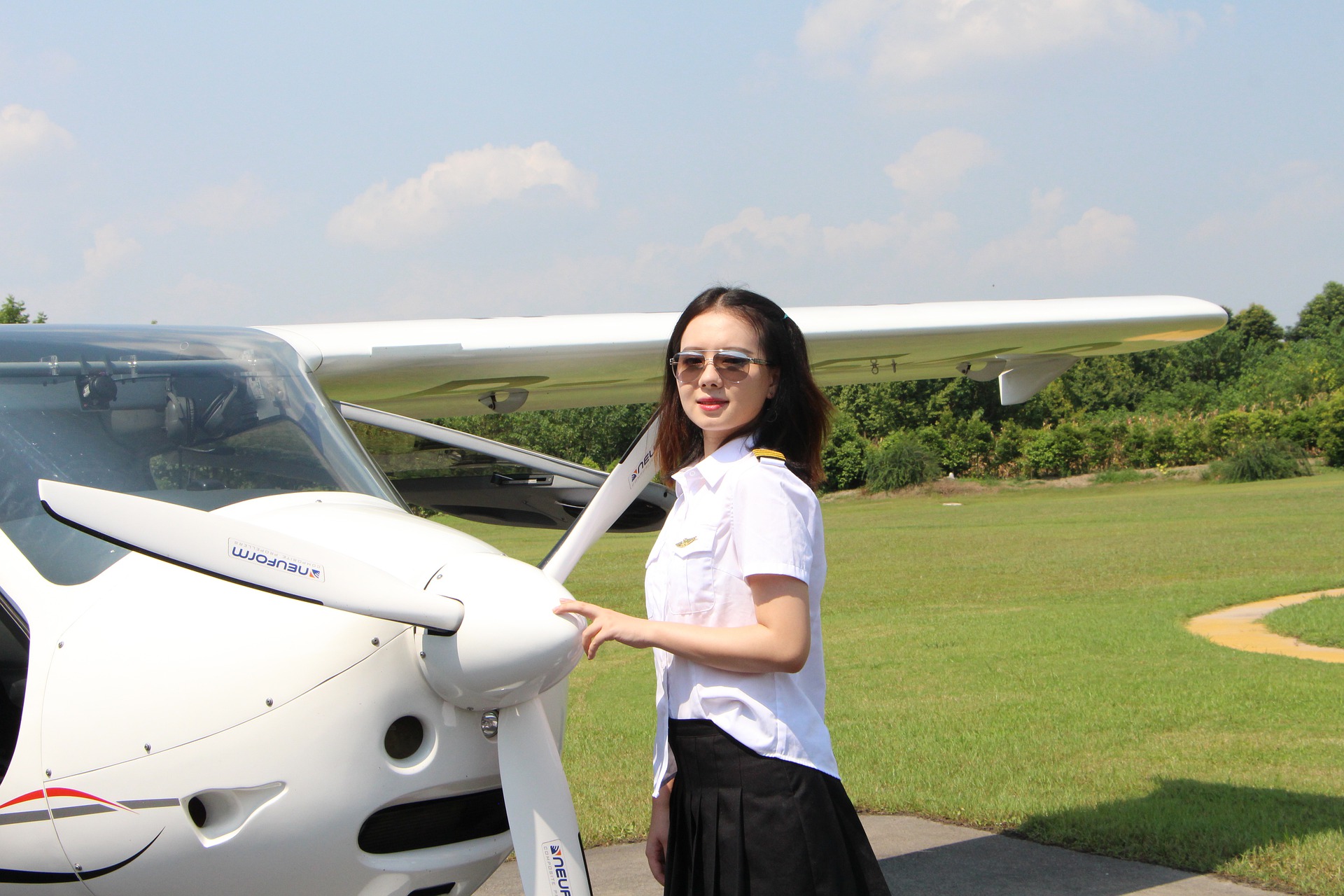 Woman aviator standing by small plane.