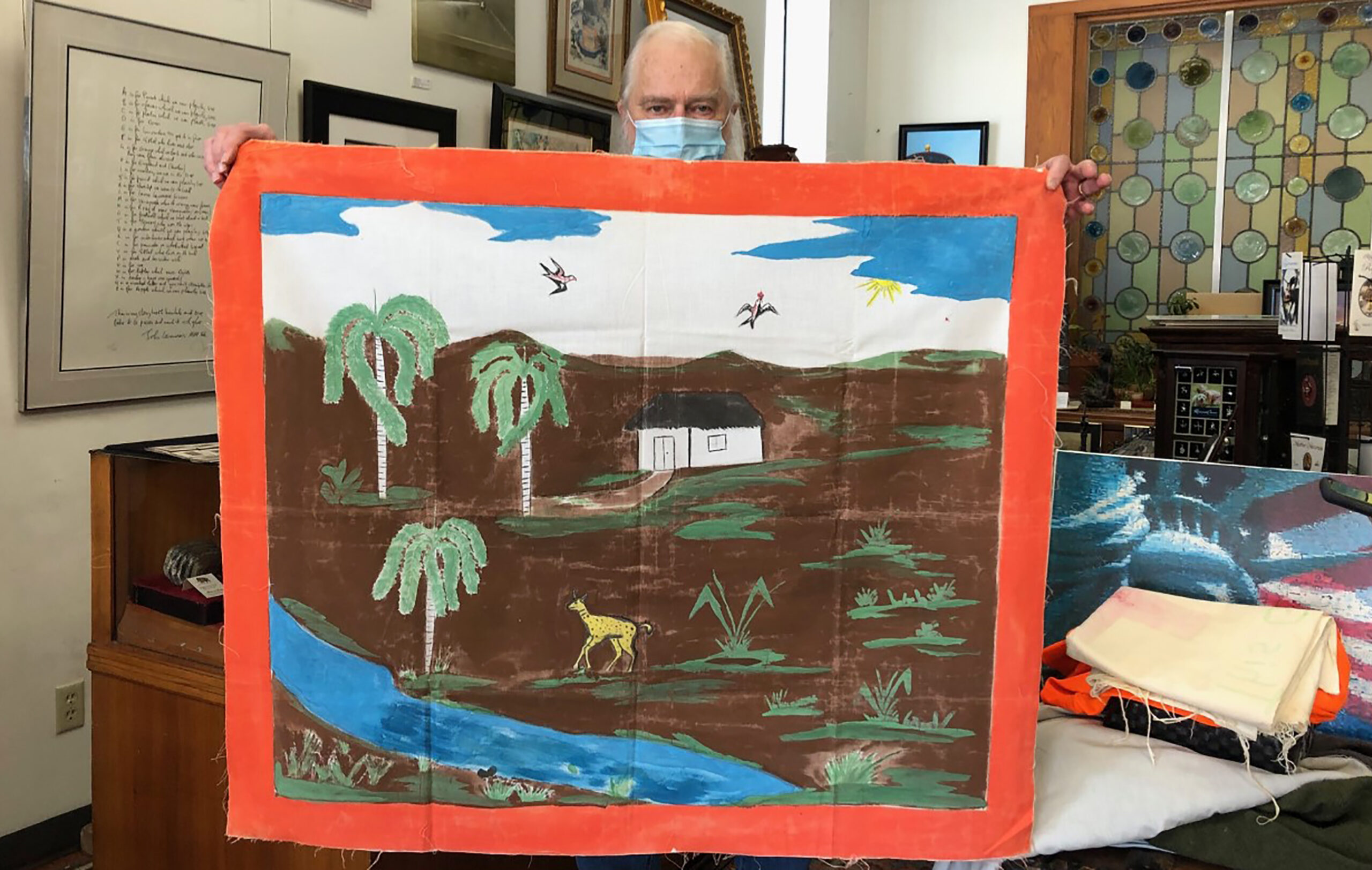 John Satory holds a painting of life in Cuba.
