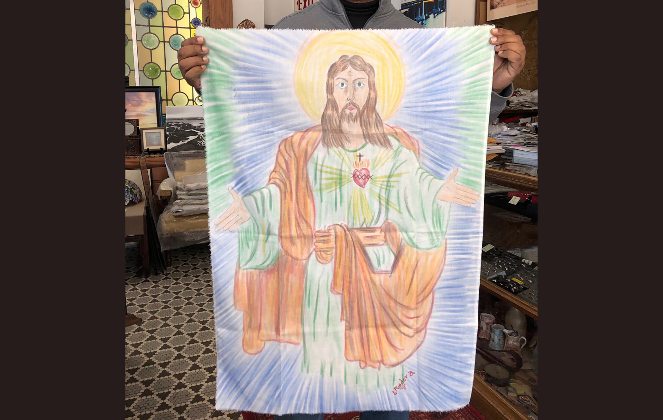 Armando Rodriguez holds art created on a bedsheet of Jesus Christ.