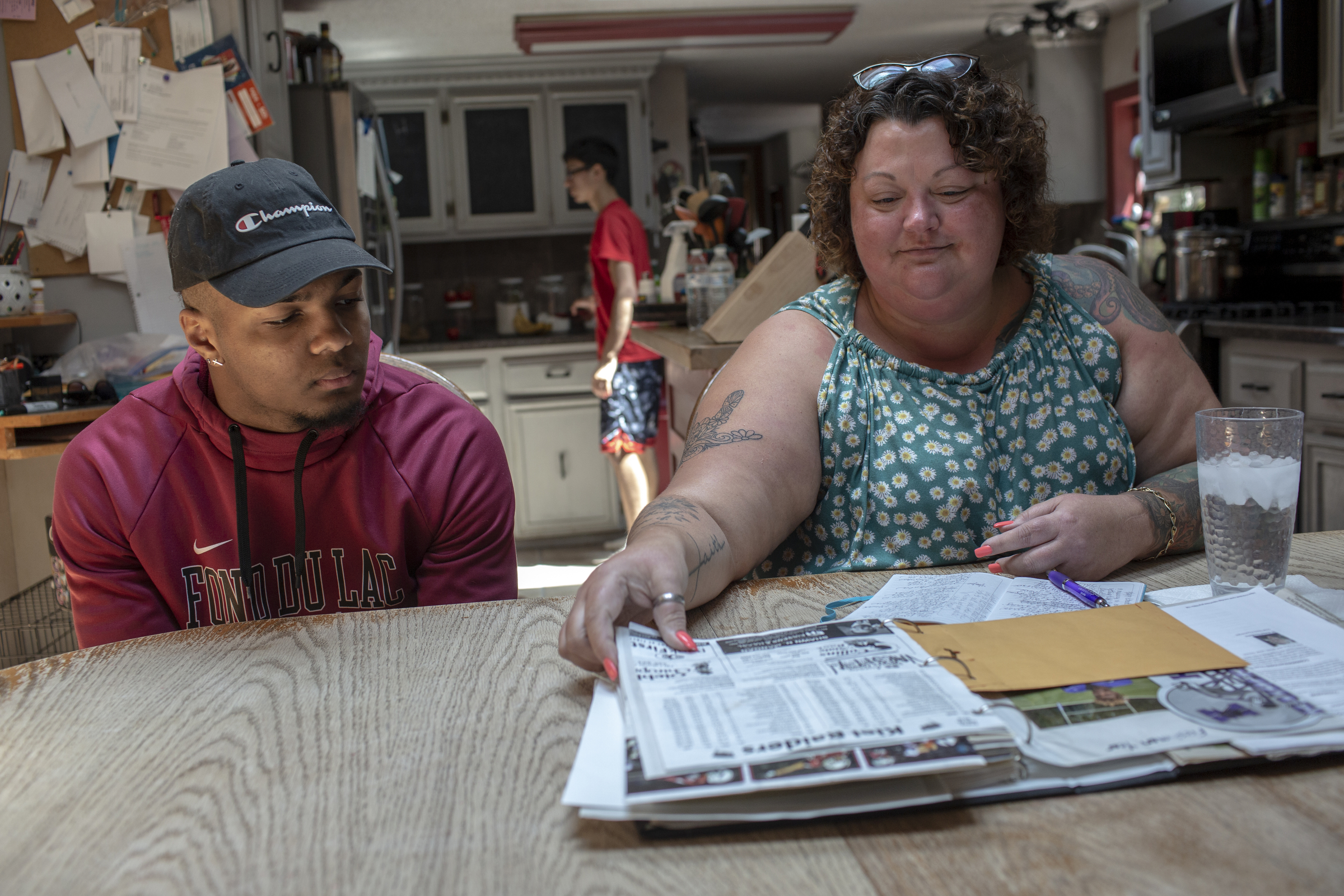Amy Wempner and her son, Armond, 18, look over a scrapbook of articles and photos of his time playing high school sports.