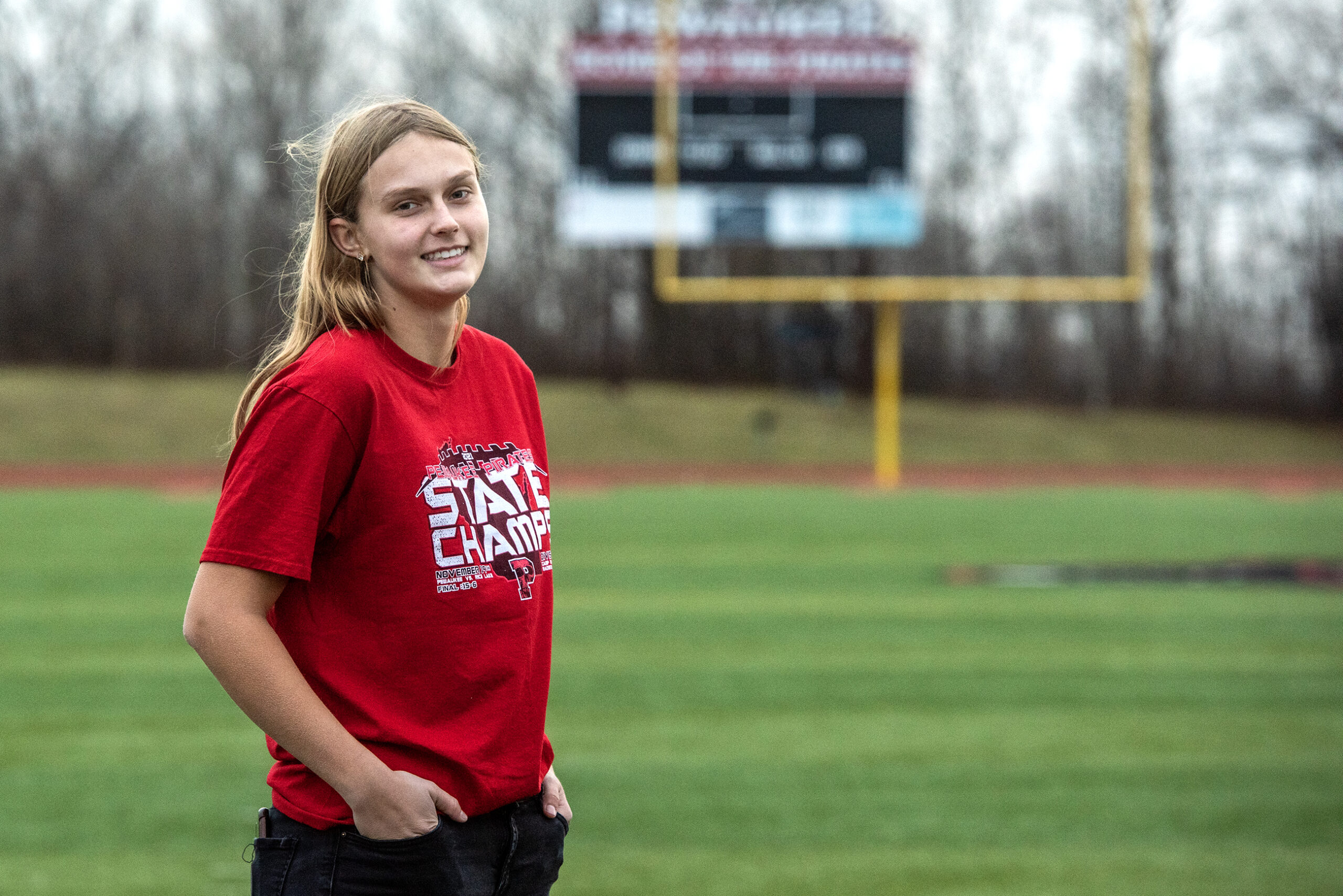 Ava Matz wears a red t shirt while standing on the football field.