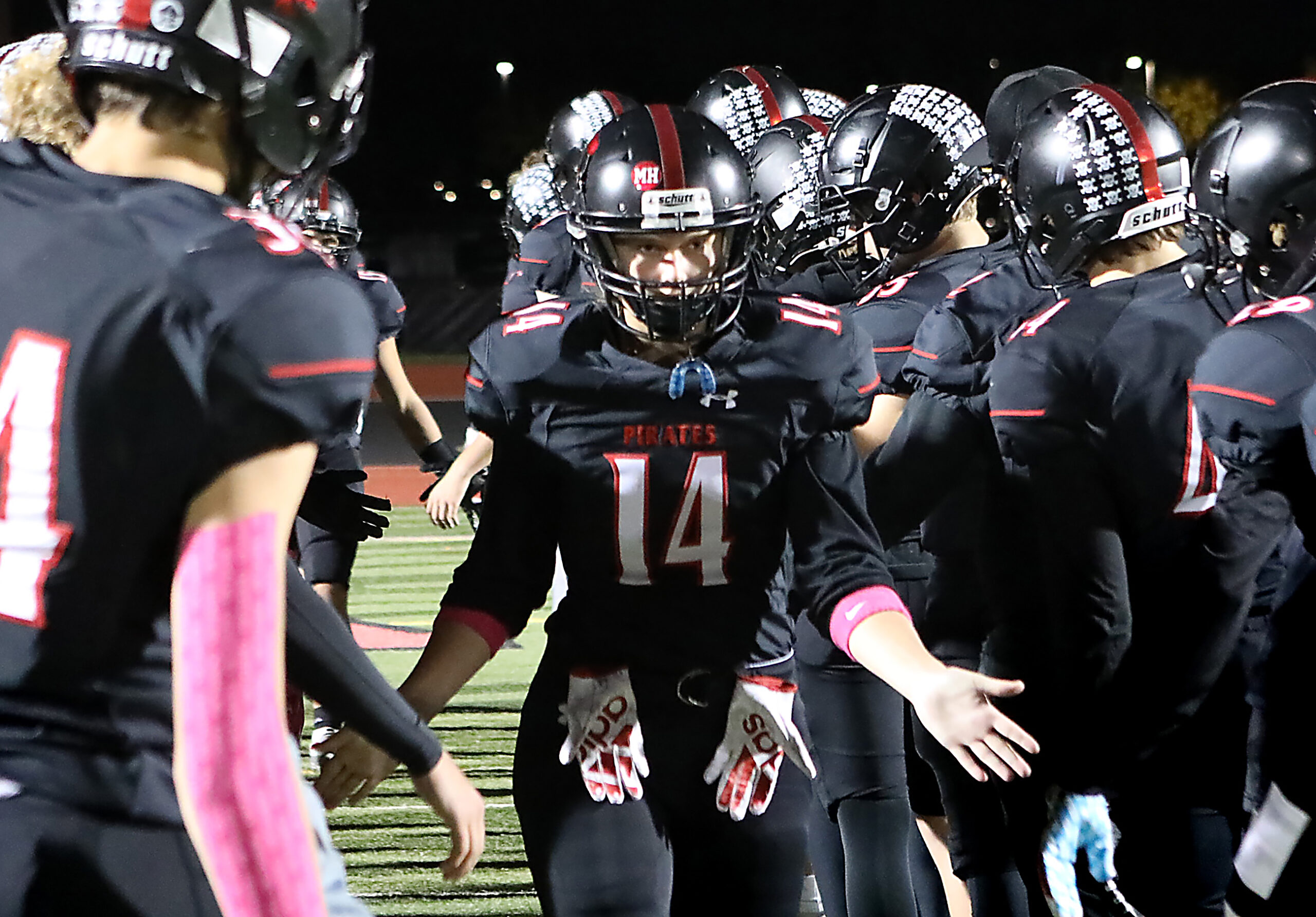 Ava Matz wears a black football uniform as she walks by her teammates.