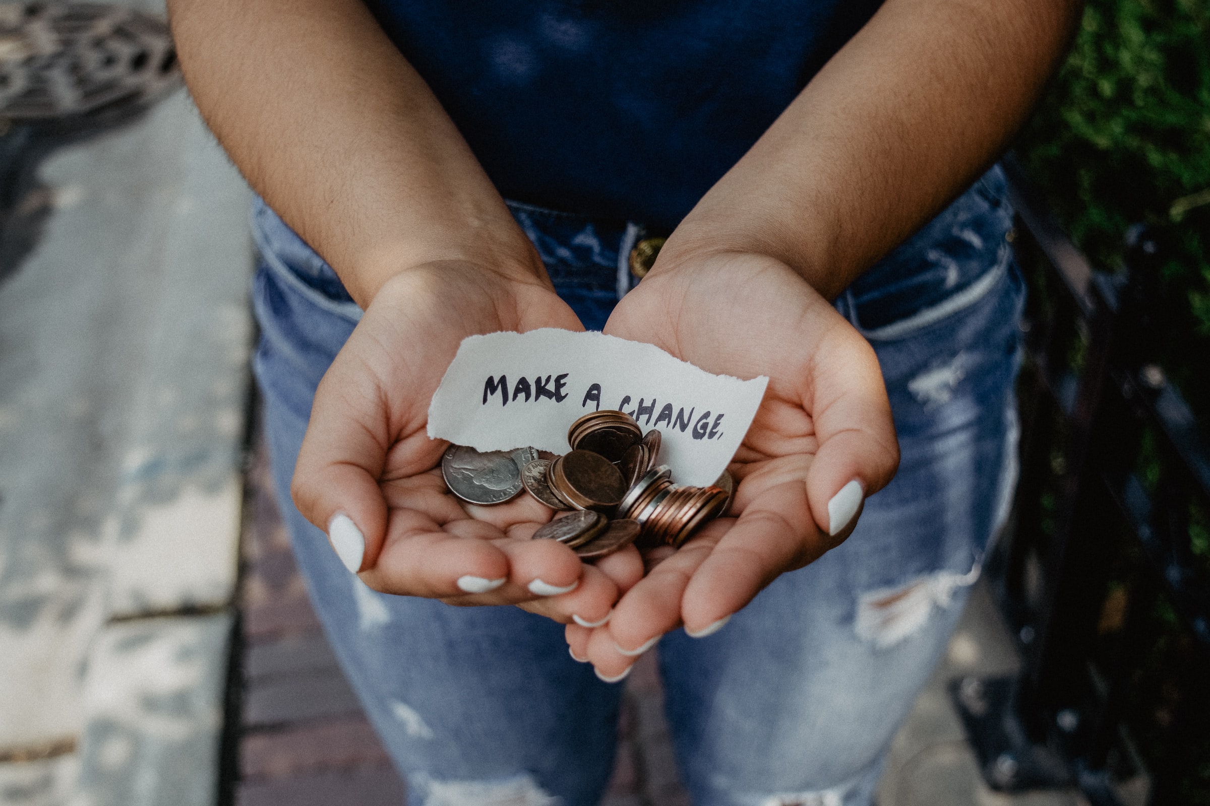 A woman holding out her hands filled with change and a note that reads "make a change."