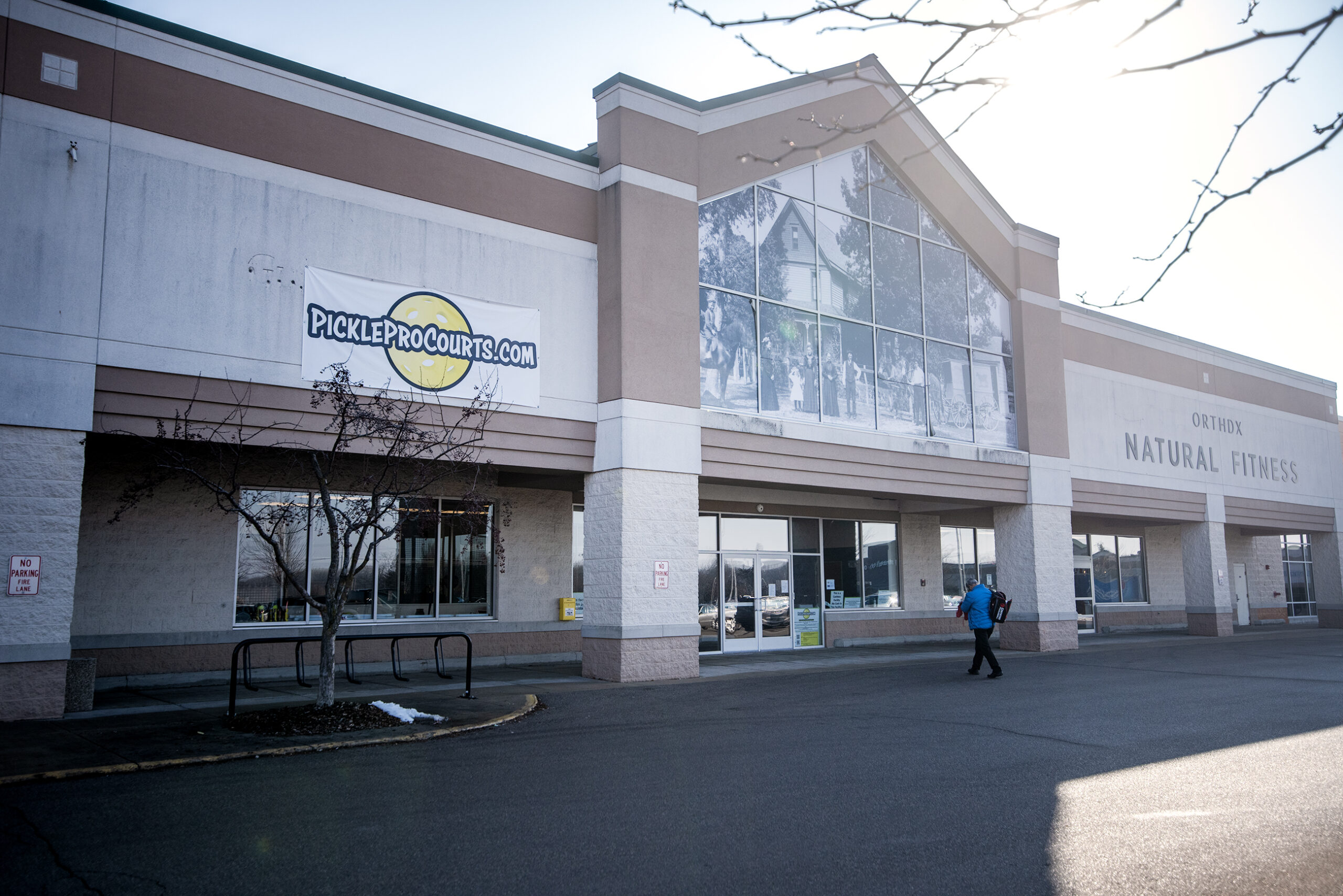 A man walks into a pickleball facility with a bag of gear.