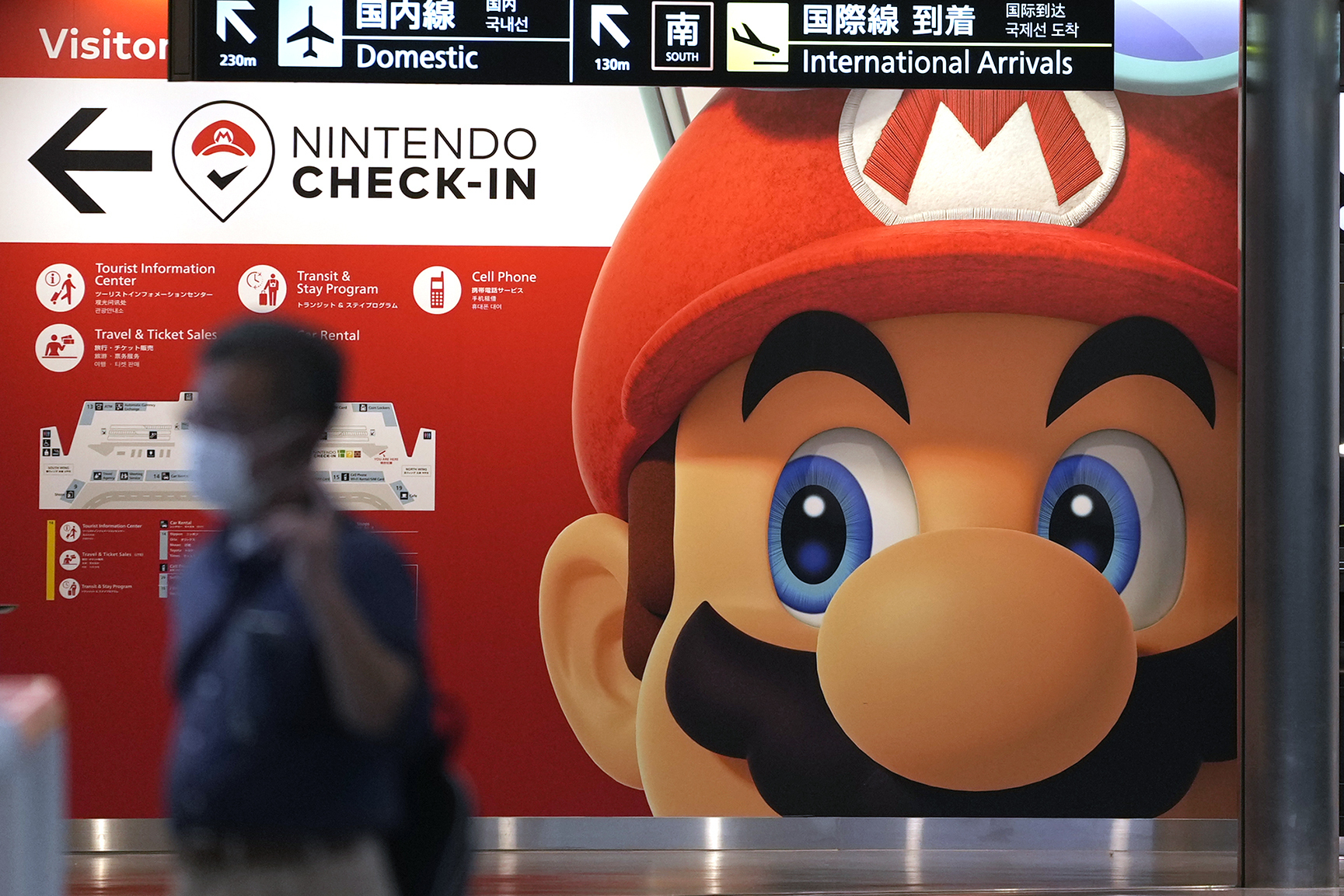 A person walks in front of a Super Mario display