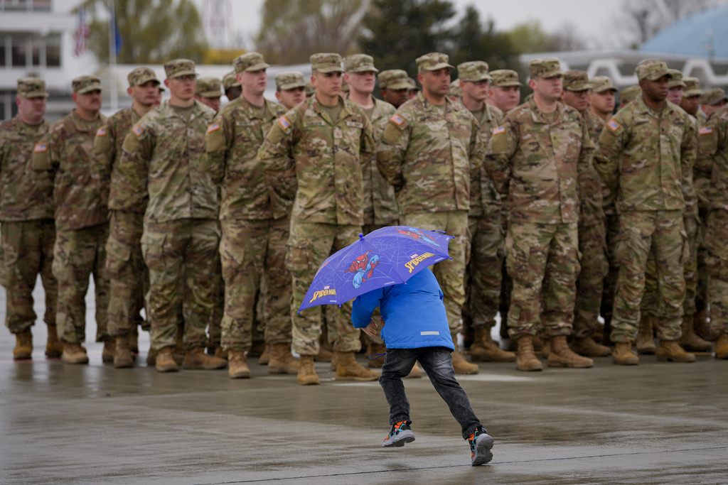 A child runs by servicemen of the United States 101 Airborne Division during a ceremony at the Mihail Kogalniceanu Air Base, near the Black Sea port of Constanta, Romania, Friday, March 31, 2023.