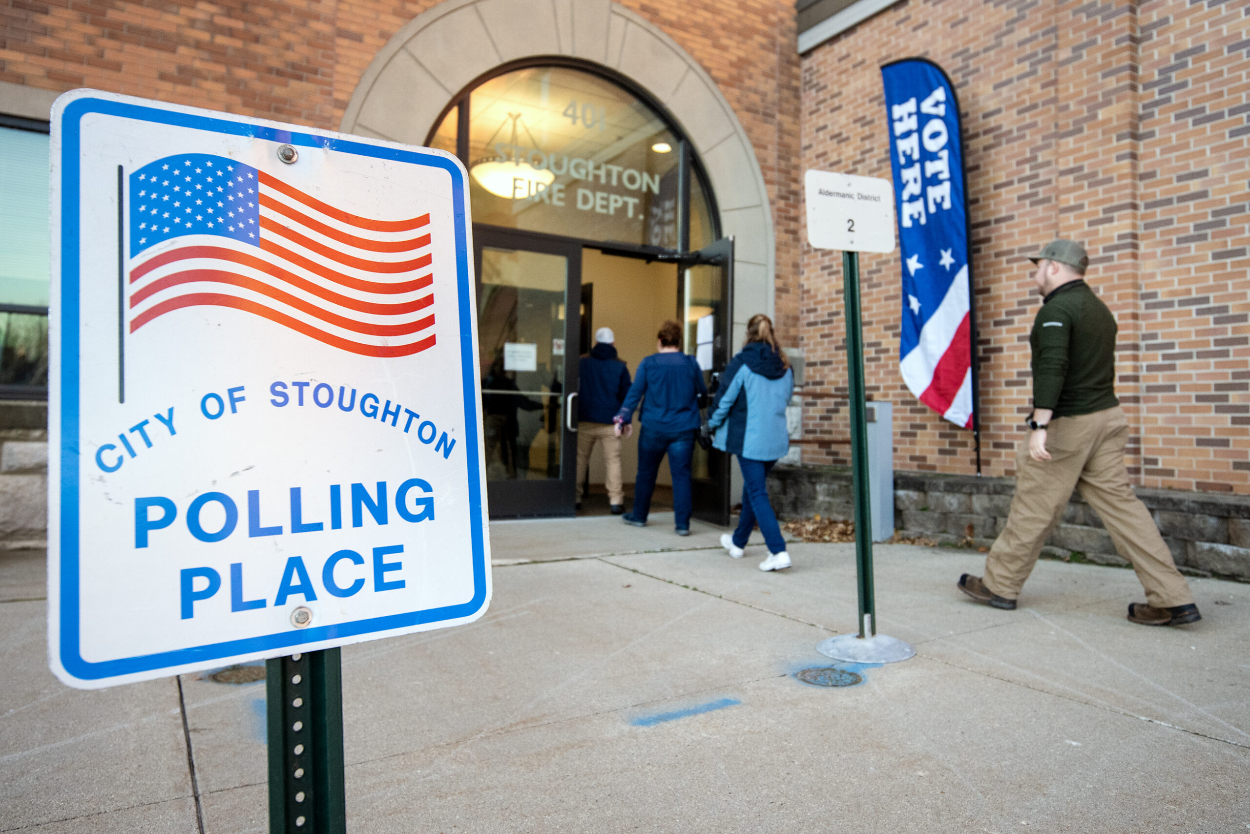 A line of voters walk past a sign that says 