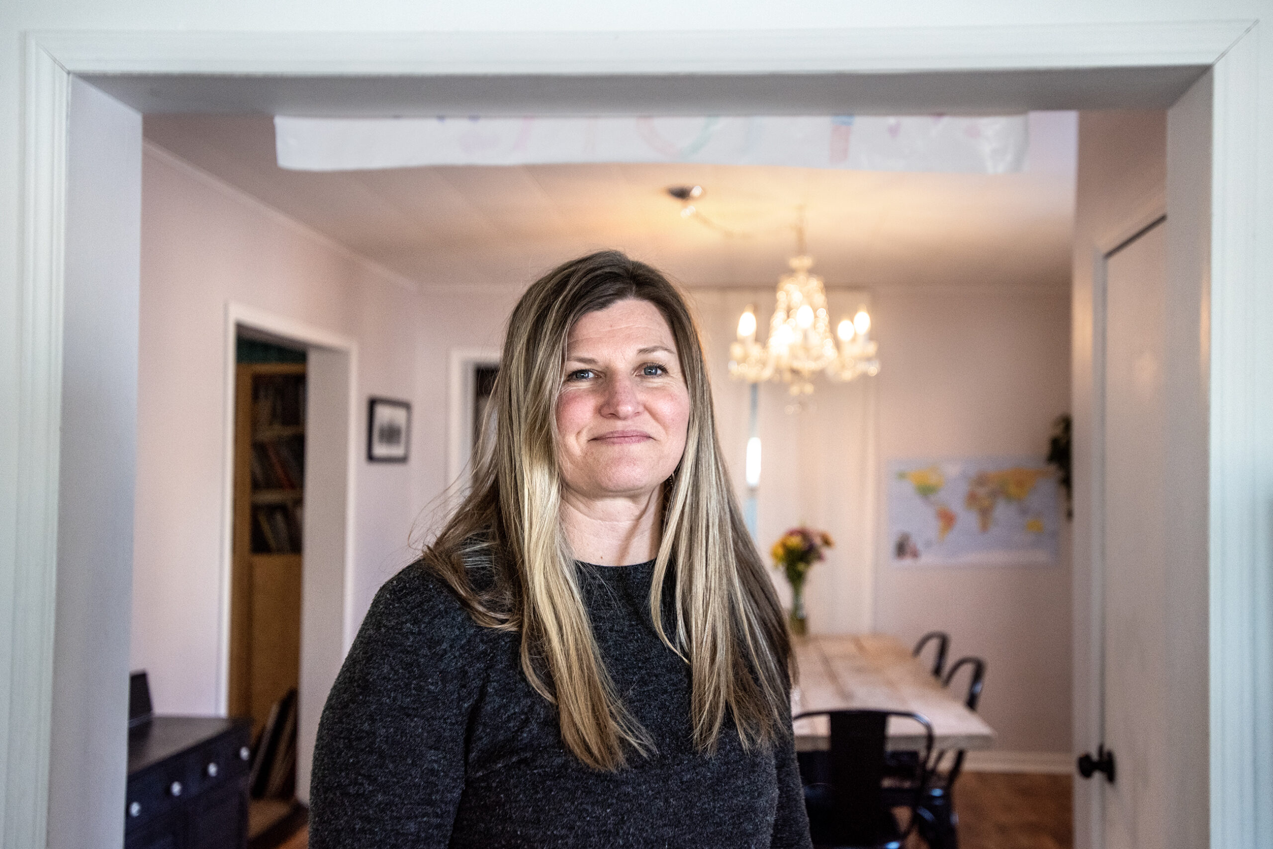 A woman stands in the doorway of an interior room in her home.