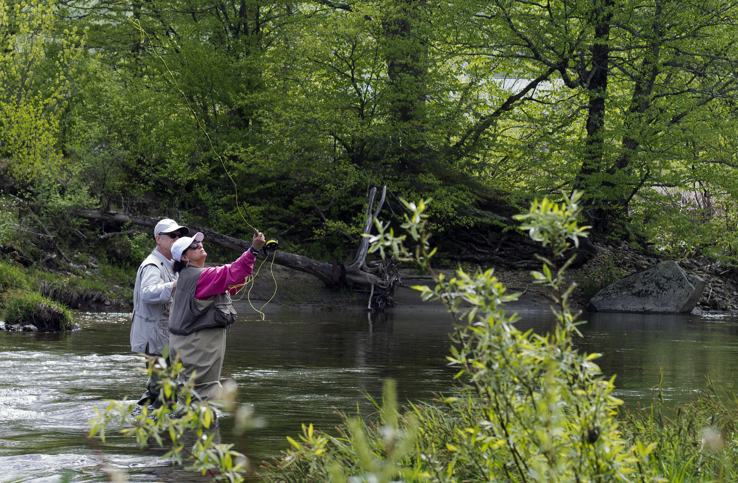 Two people fly fish in a river.