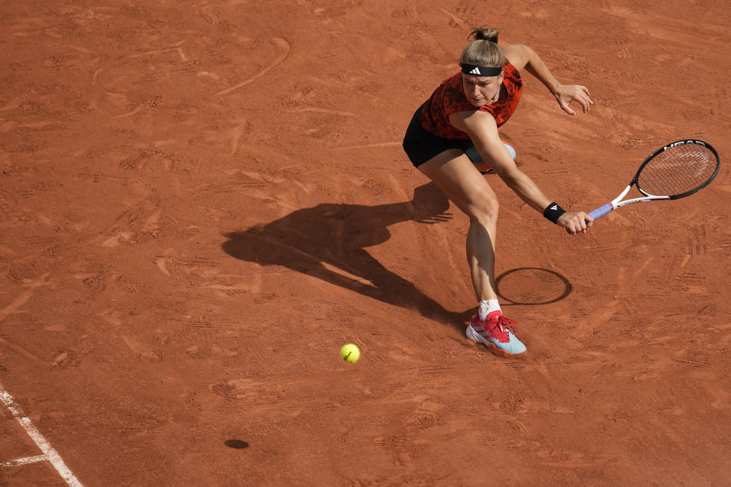 Iga Swiatek swings her racket at a tennis ball flying over the net