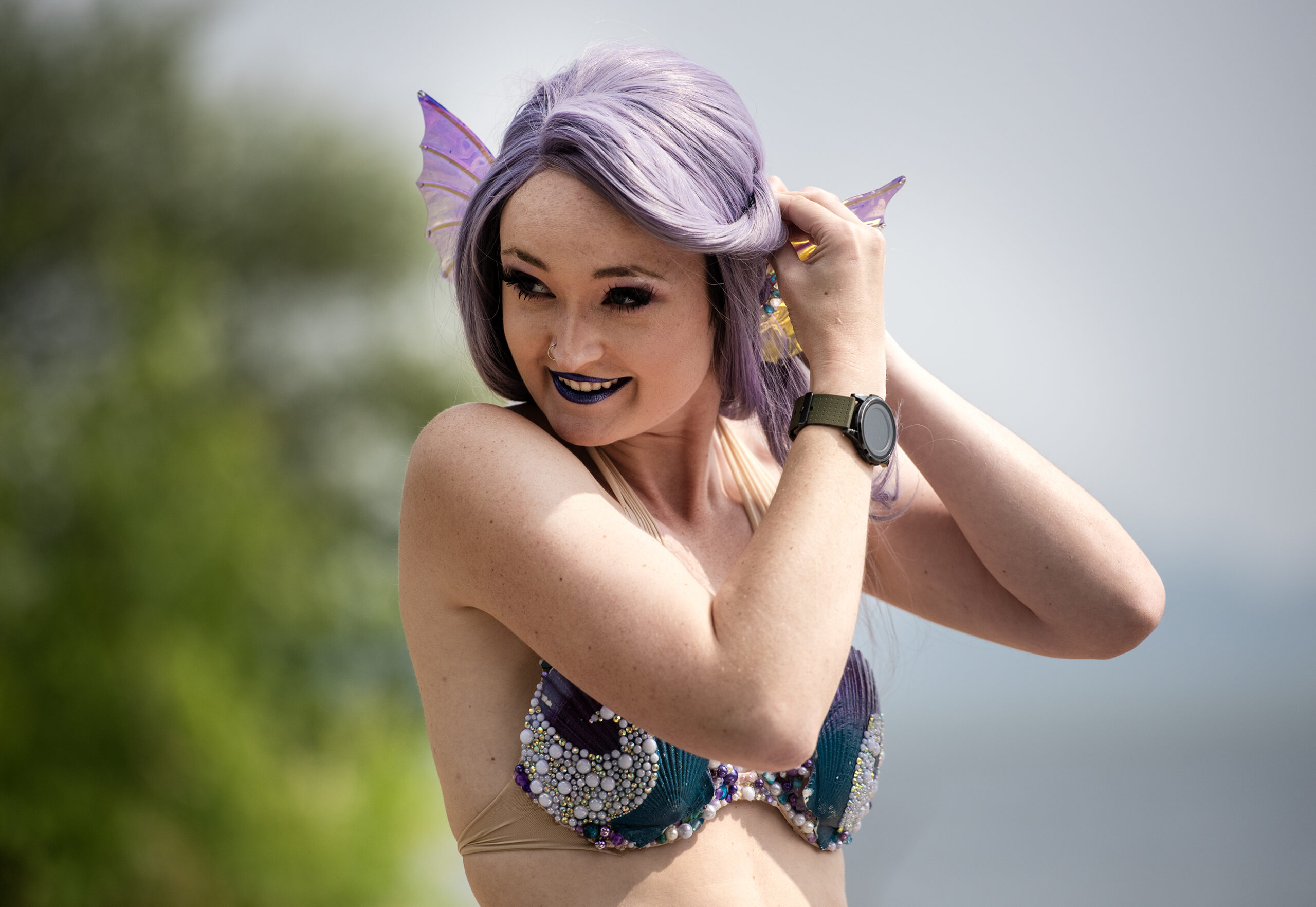 Echo pulls back purple hair while pinning on mermaid ears.