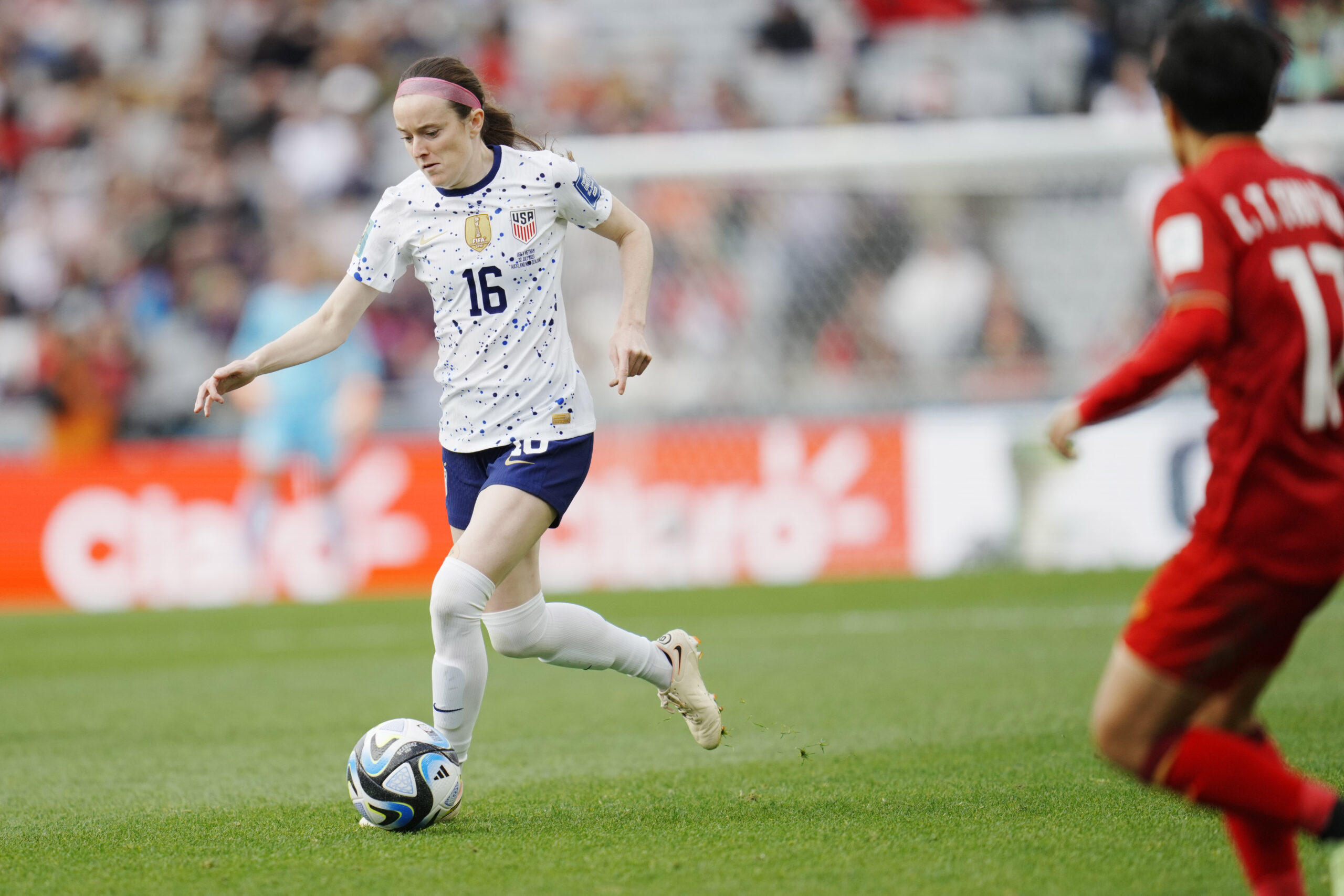 Rose Lavelle dribbles a ball down the pitch. A defender hovers to her right.