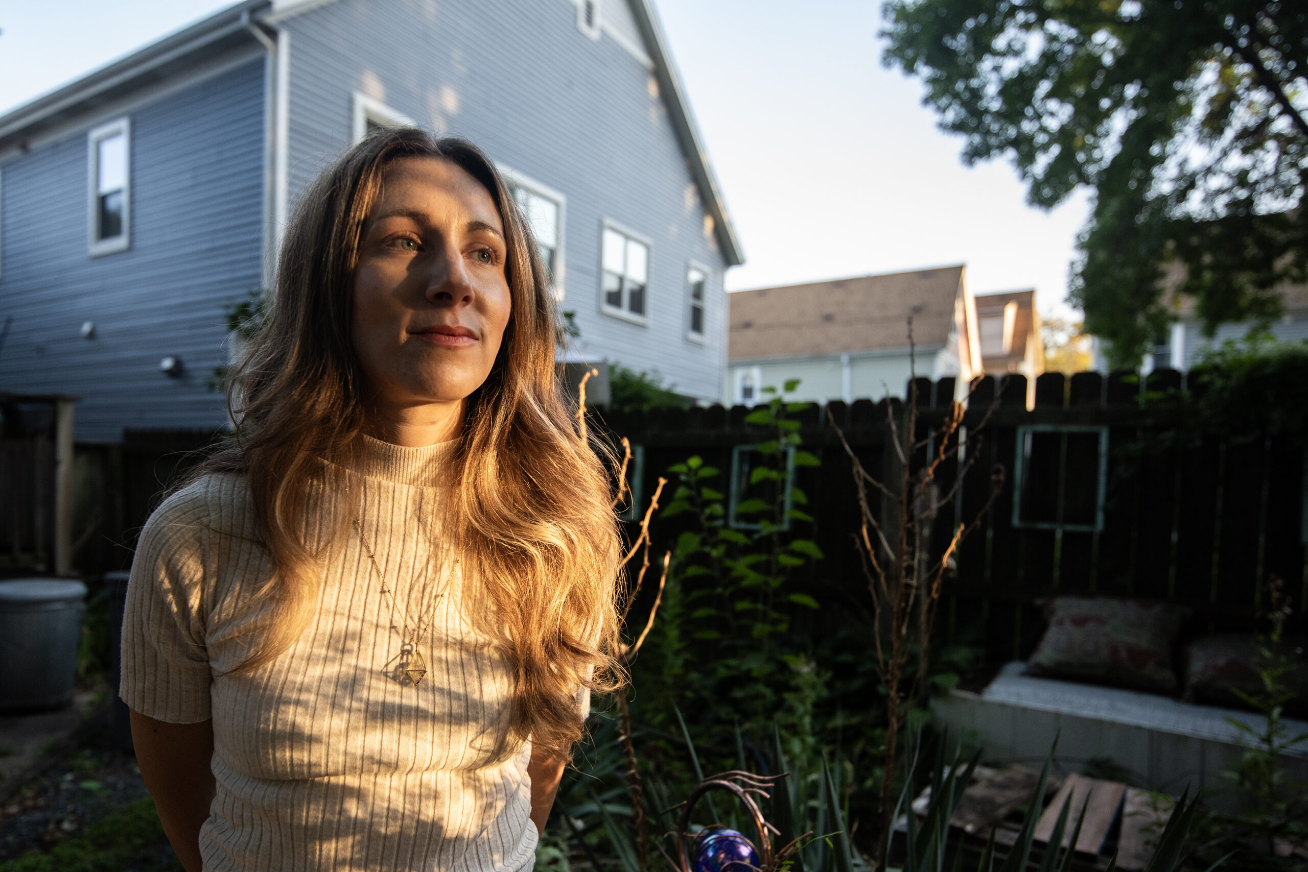 Evening light shines on Megan as she stands outside.