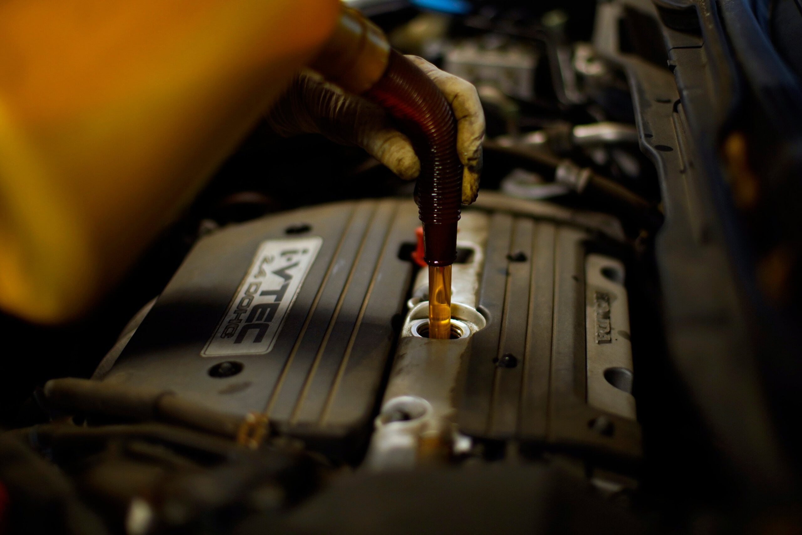 A mechanic fills a car with oil at an auto repair shop