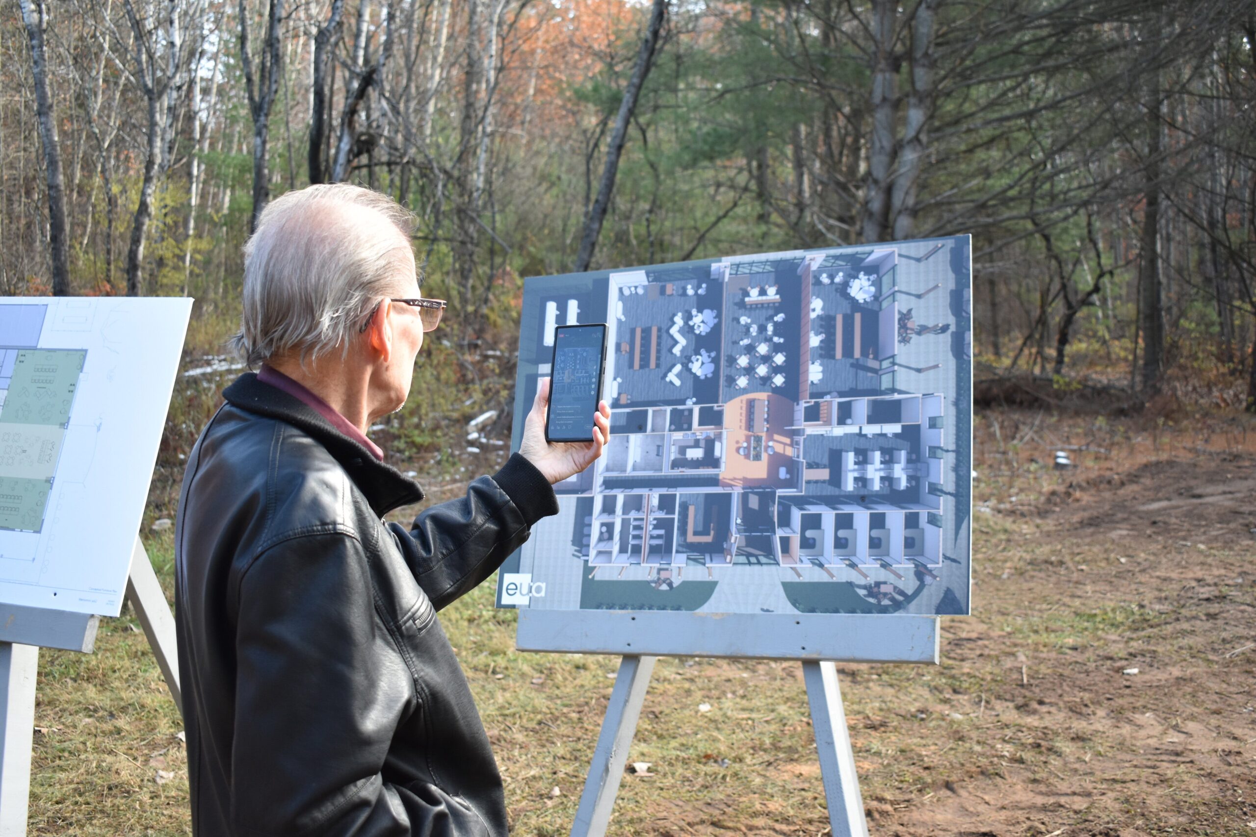 A man takes a photo of a rendering of the language center's proposed floor plan.