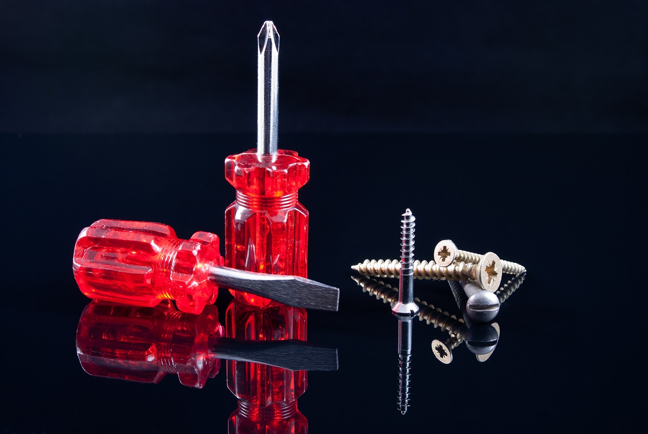 Red screwdrivers and screws with a black background.