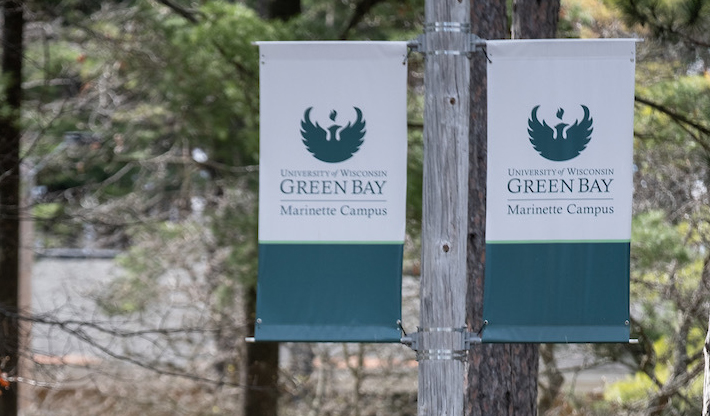 White and teal flags say "University of Wisconsin-Green Bay Marinette Campus"