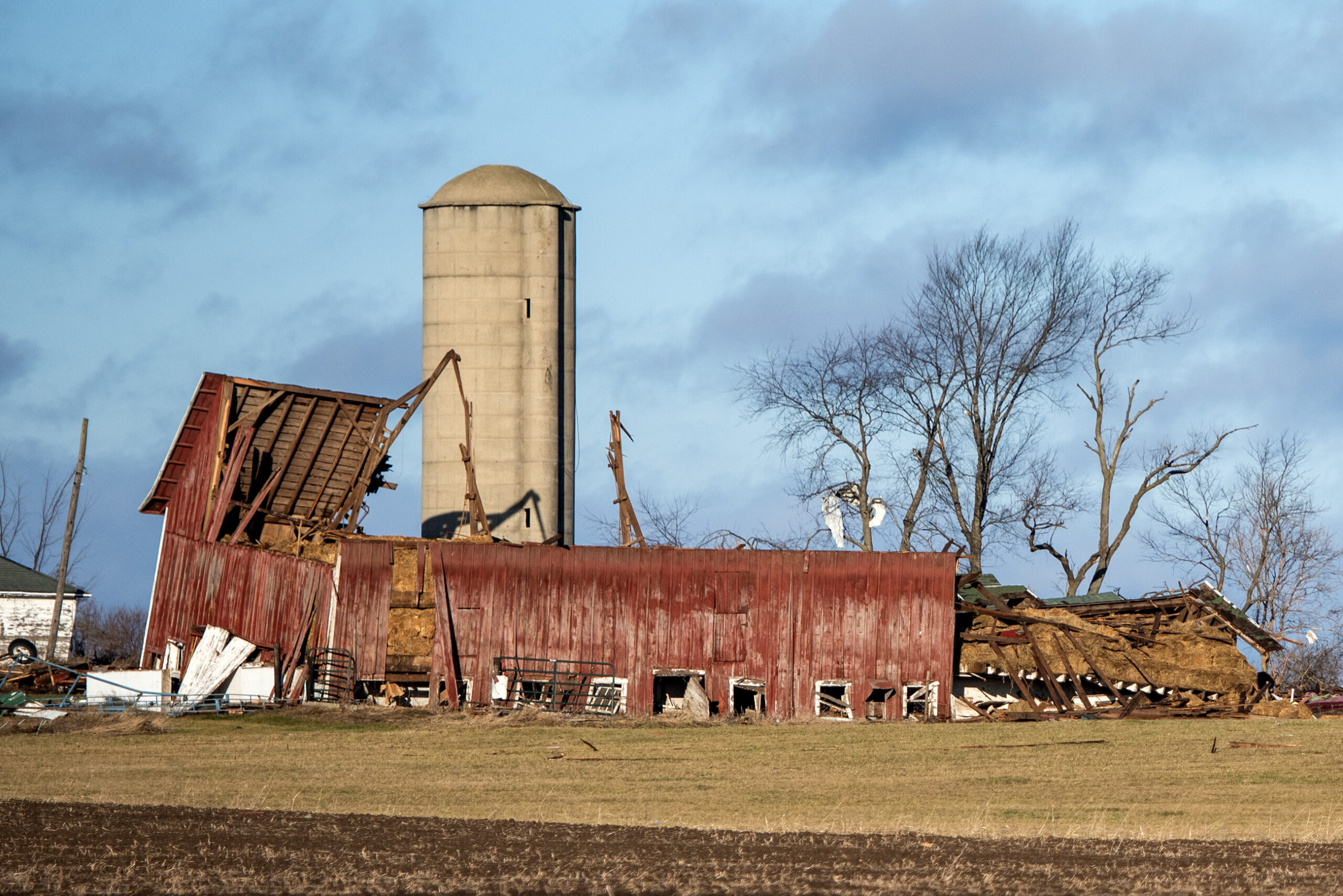 A barn's roof is torn off.